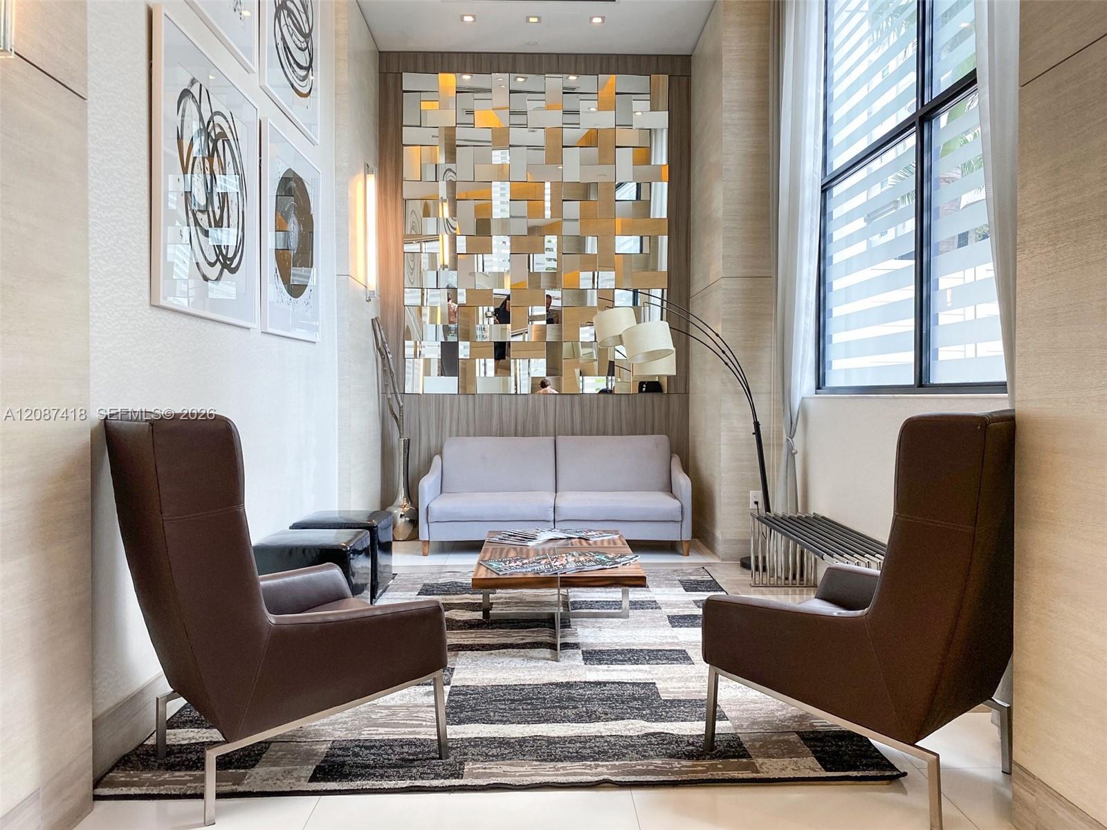 Condominium lobby seating with brown armchairs, a light sofa, and a decorative mirrored wall.