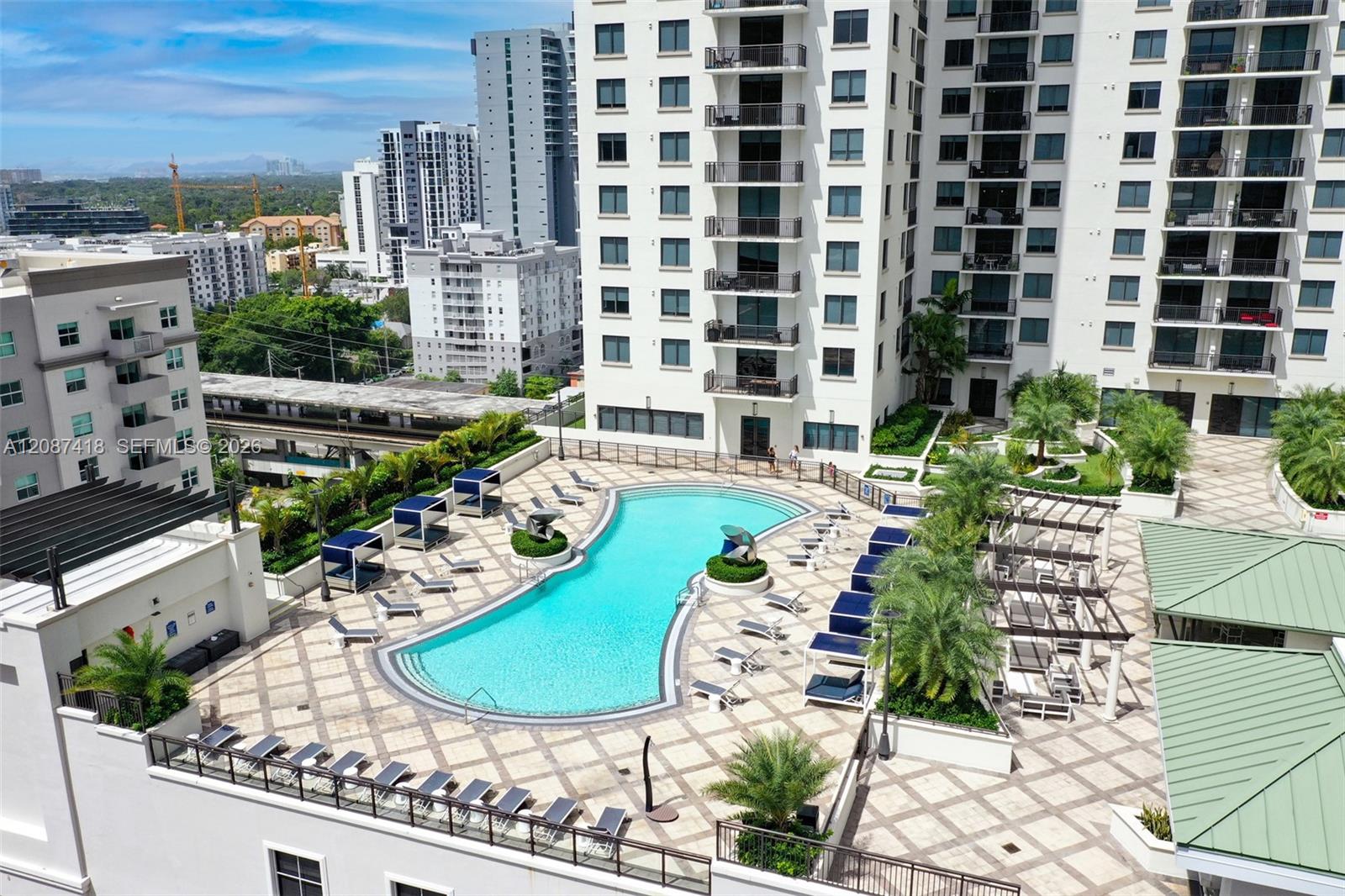 High-rise courtyard pool with a tiled sun deck, lounge chairs, palm trees, and surrounding apartment towers.