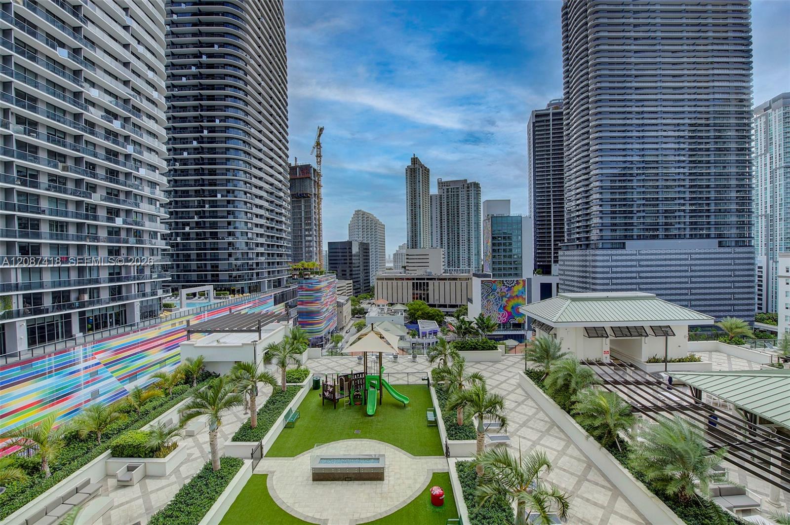 Condominium courtyard with a playground and palm trees, surrounded by downtown high-rises.