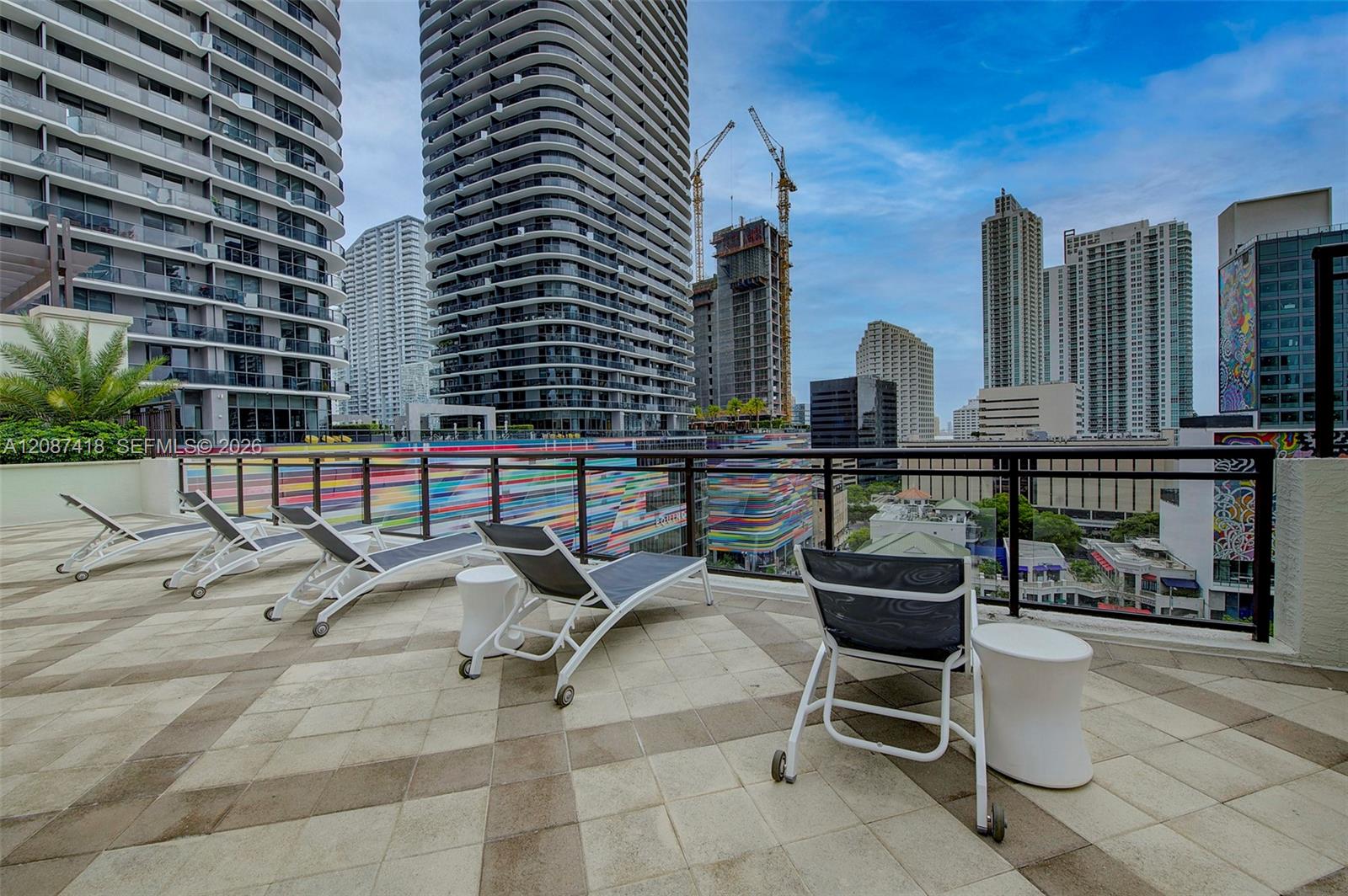 Rooftop terrace with lounge chairs overlooking Miami high-rises and a colorful striped building.