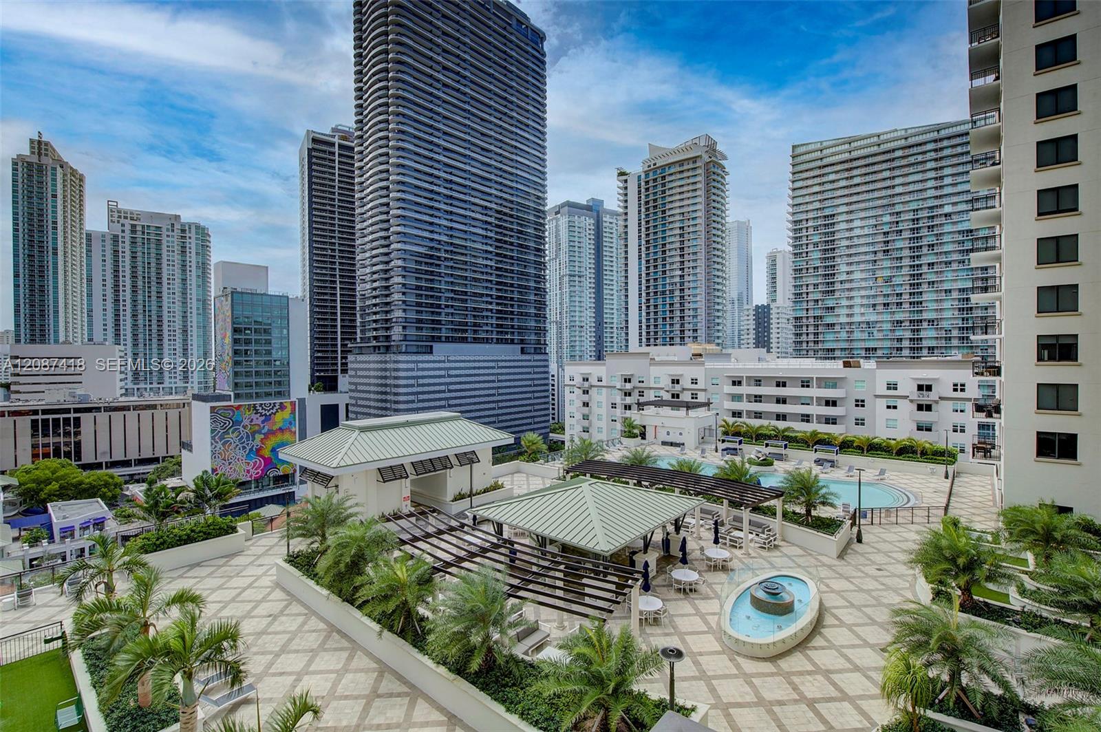 Rooftop pool deck with palm trees and seating, surrounded by Miami high-rises.