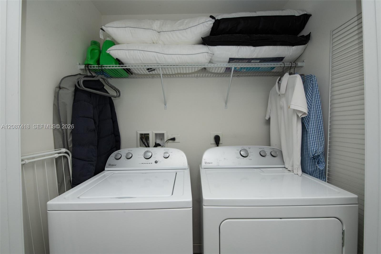 Laundry closet with a top-loading washer, front-loading dryer, and storage shelf above.