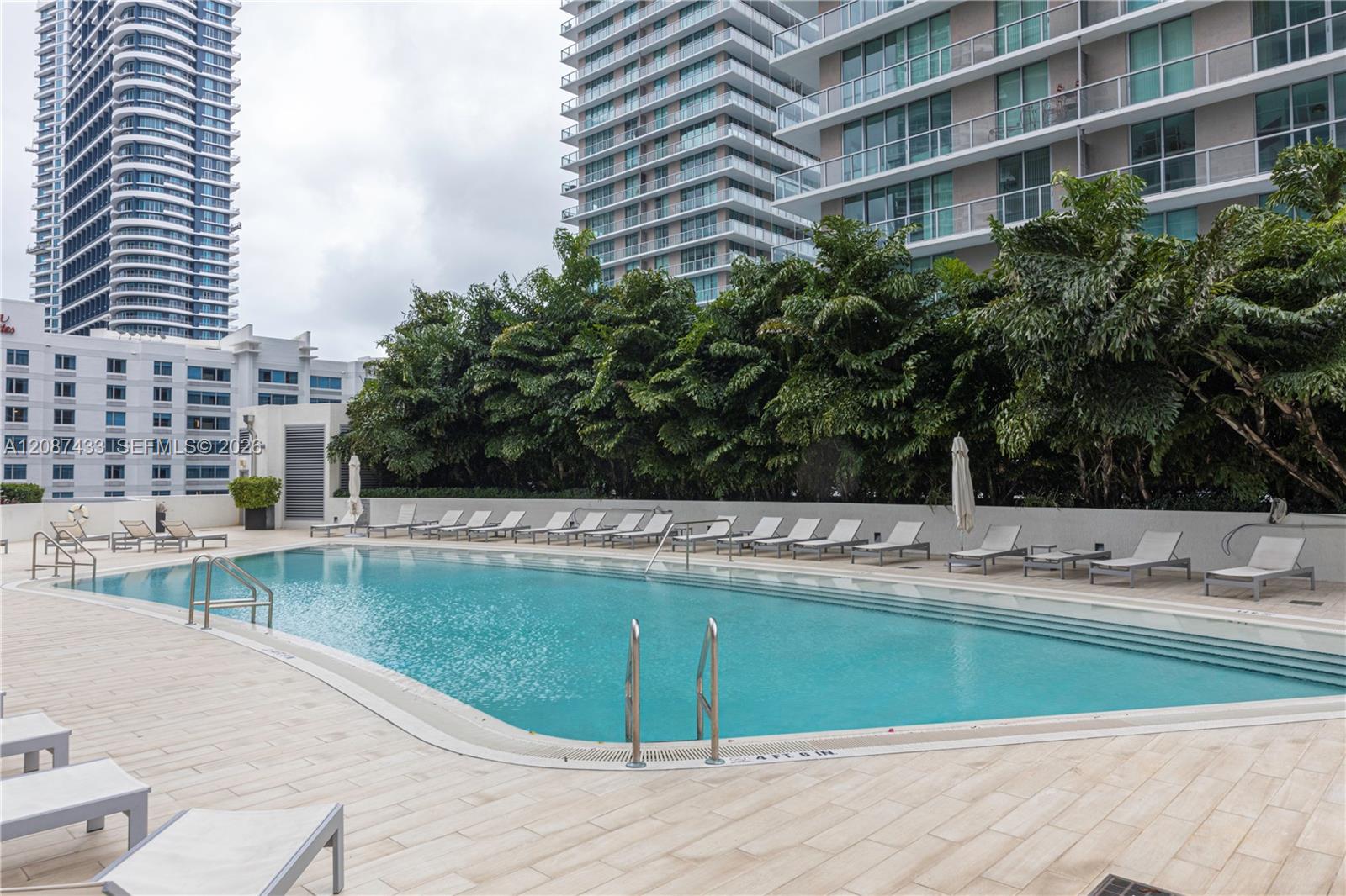 Condominium pool with lounge chairs and high-rise buildings in the background.