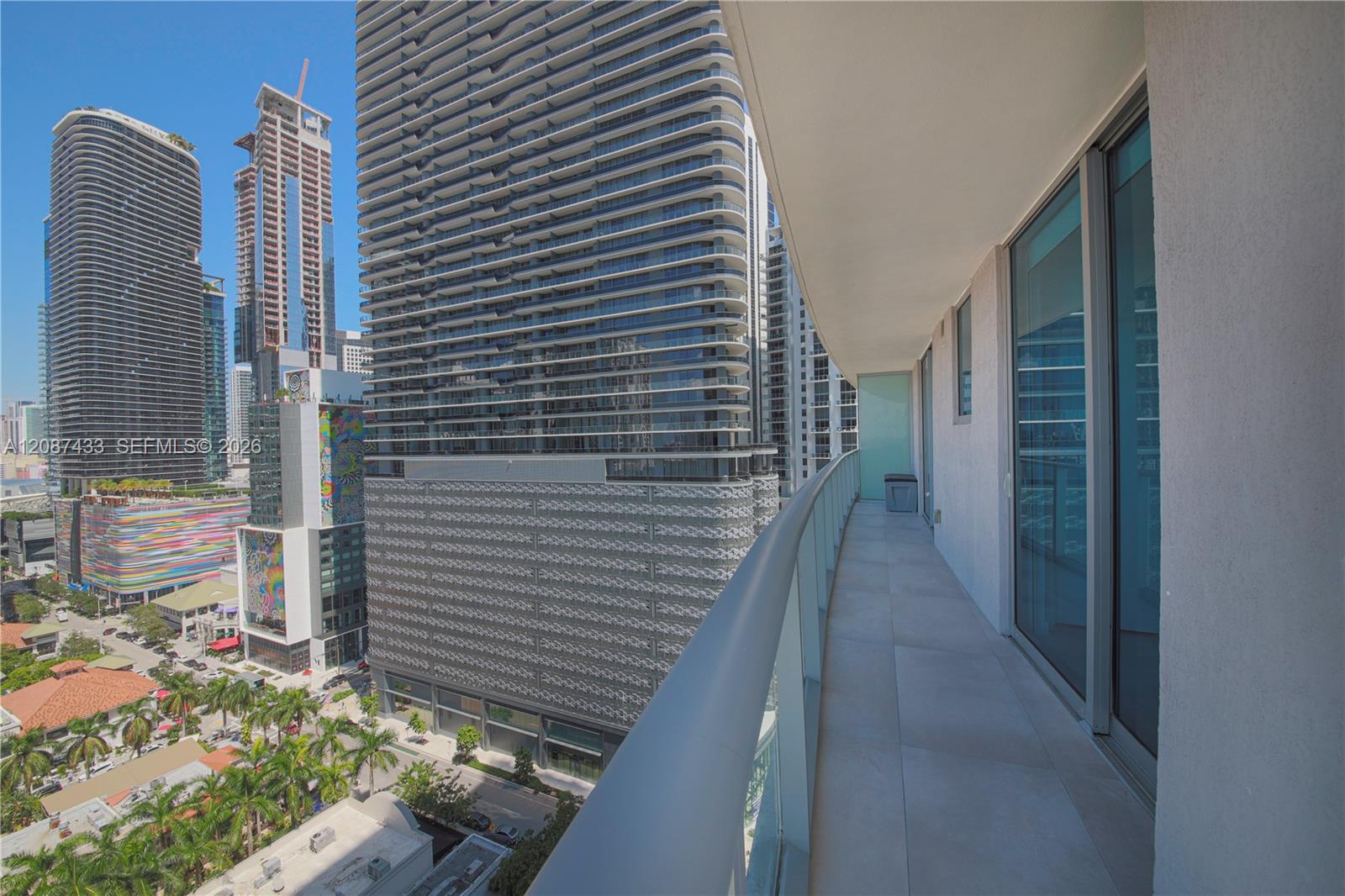 High-rise balcony overlooking downtown Miami towers and palm-lined streets.