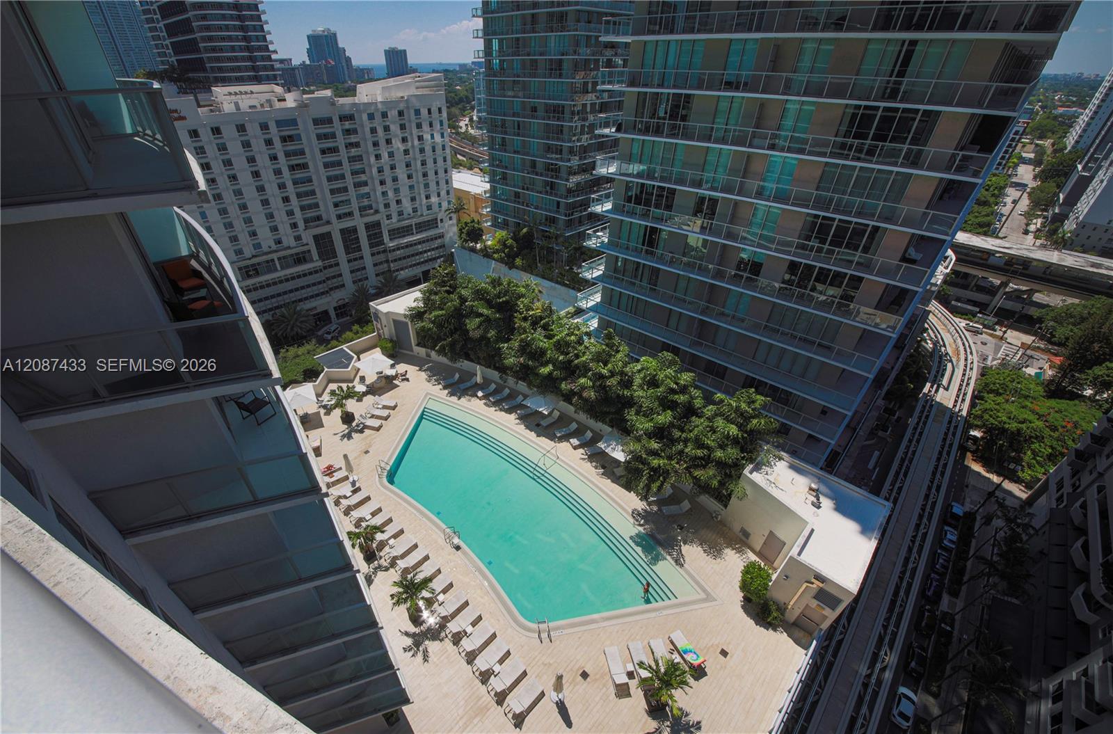 High-rise pool deck with a turquoise pool, lounge chairs, and surrounding Miami buildings.
