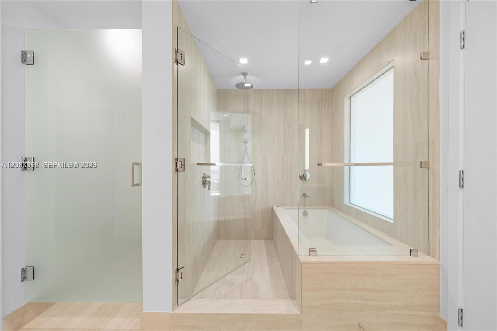 Modern bathroom with a glass walk-in shower, built-in soaking tub, and large frosted window.