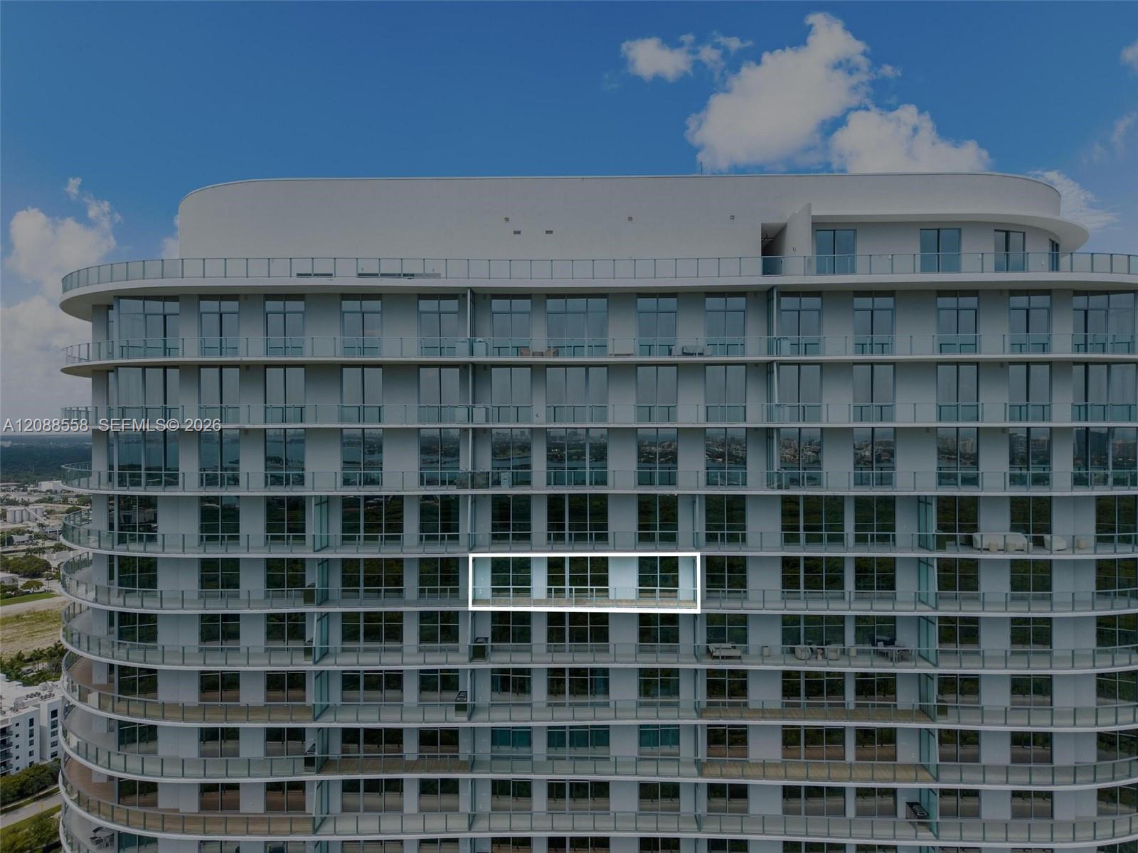 Modern high-rise exterior with glass balconies and one balcony unit outlined in white.