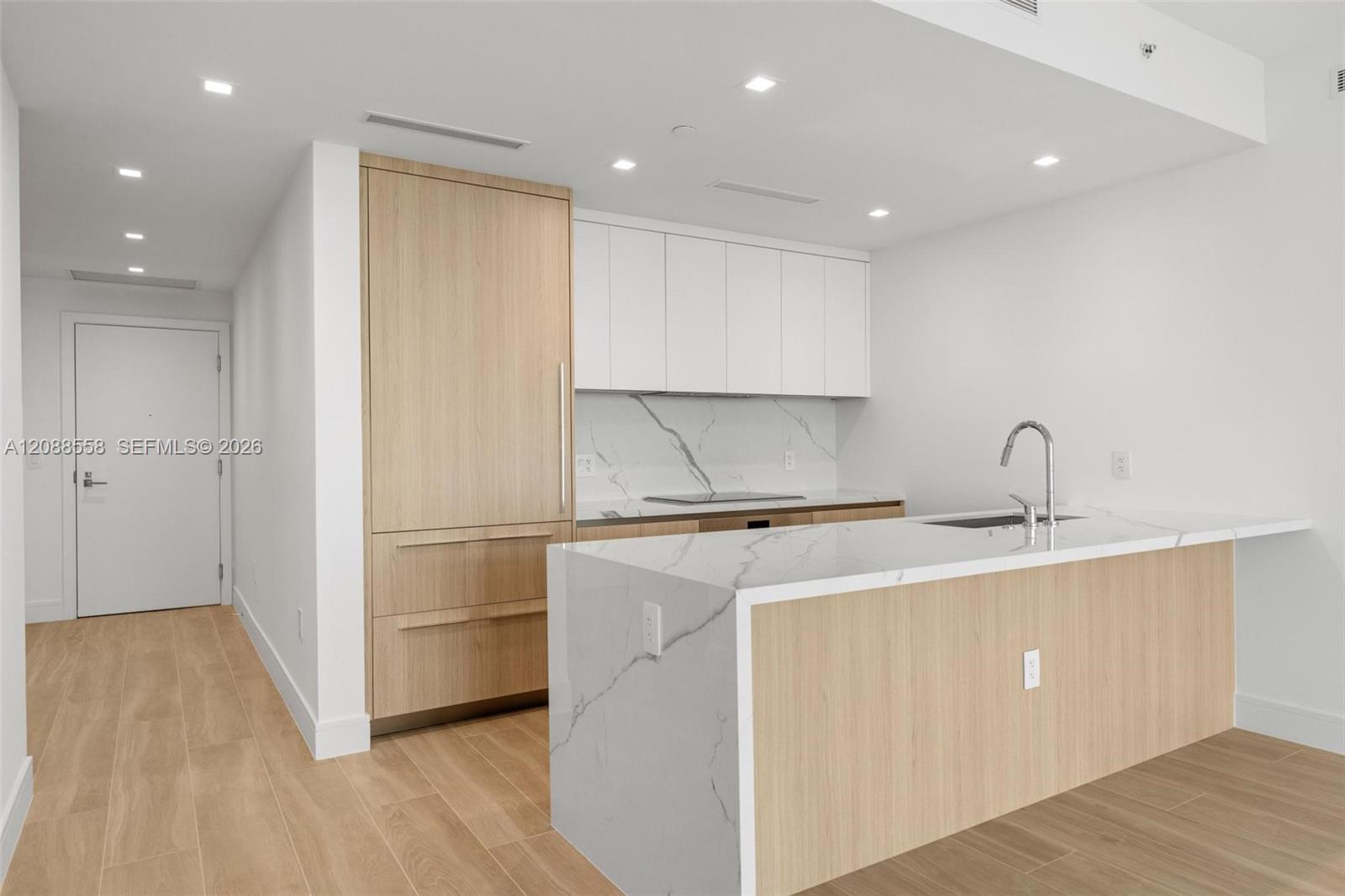 Modern kitchen with light wood cabinetry and a veined stone waterfall island.
