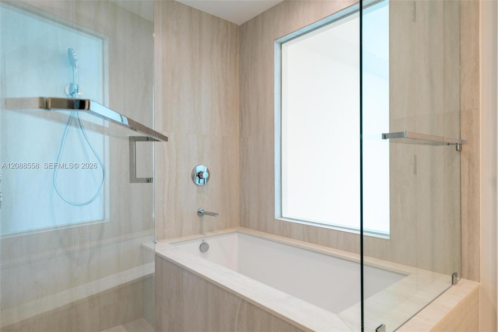 Bathroom with a built-in soaking tub beside a glass-enclosed shower and large window.