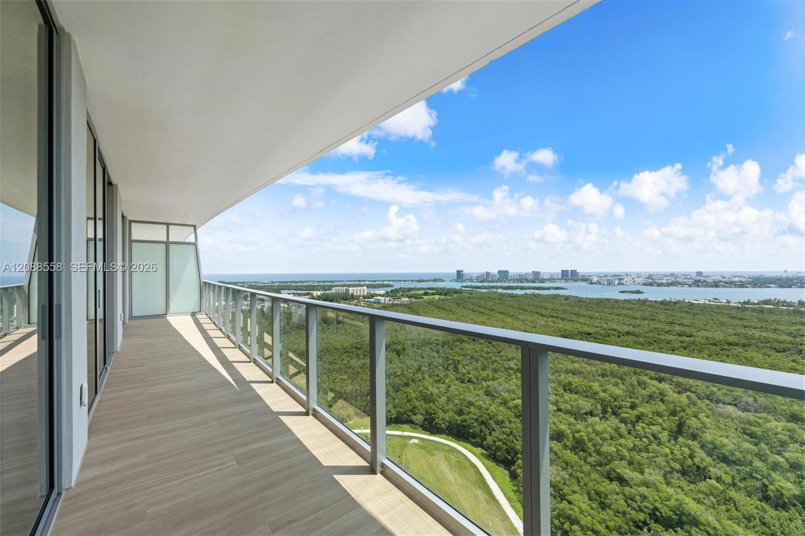 High-rise balcony overlooking a green preserve, water, and distant Miami skyline.