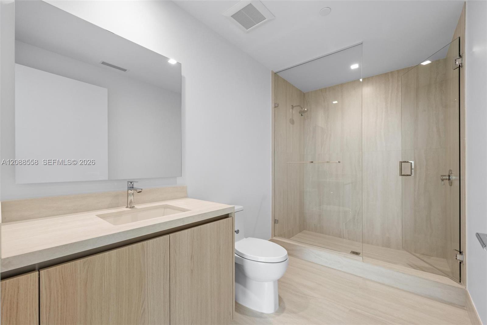 Modern bathroom with a light wood vanity and a glass-enclosed walk-in shower.