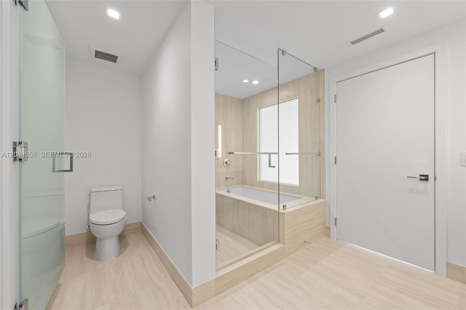 Modern bathroom with a glass-enclosed bathtub, separate shower, and toilet.