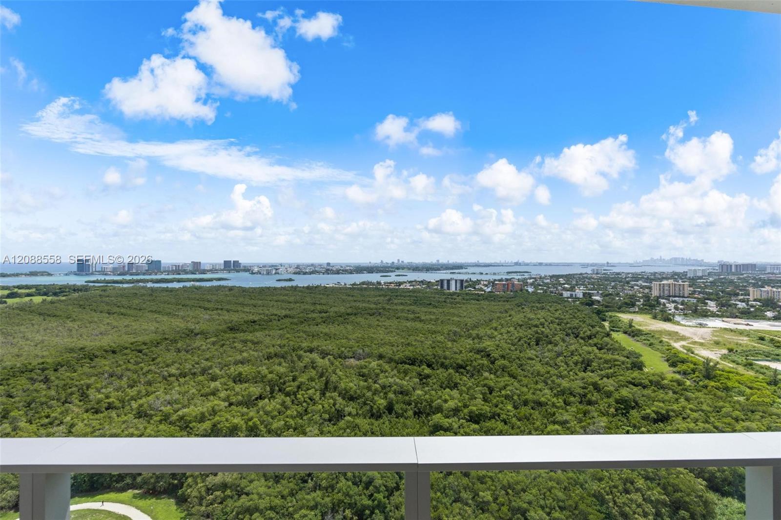 High-rise balcony view over a mangrove preserve, waterways, and distant Miami skyline.