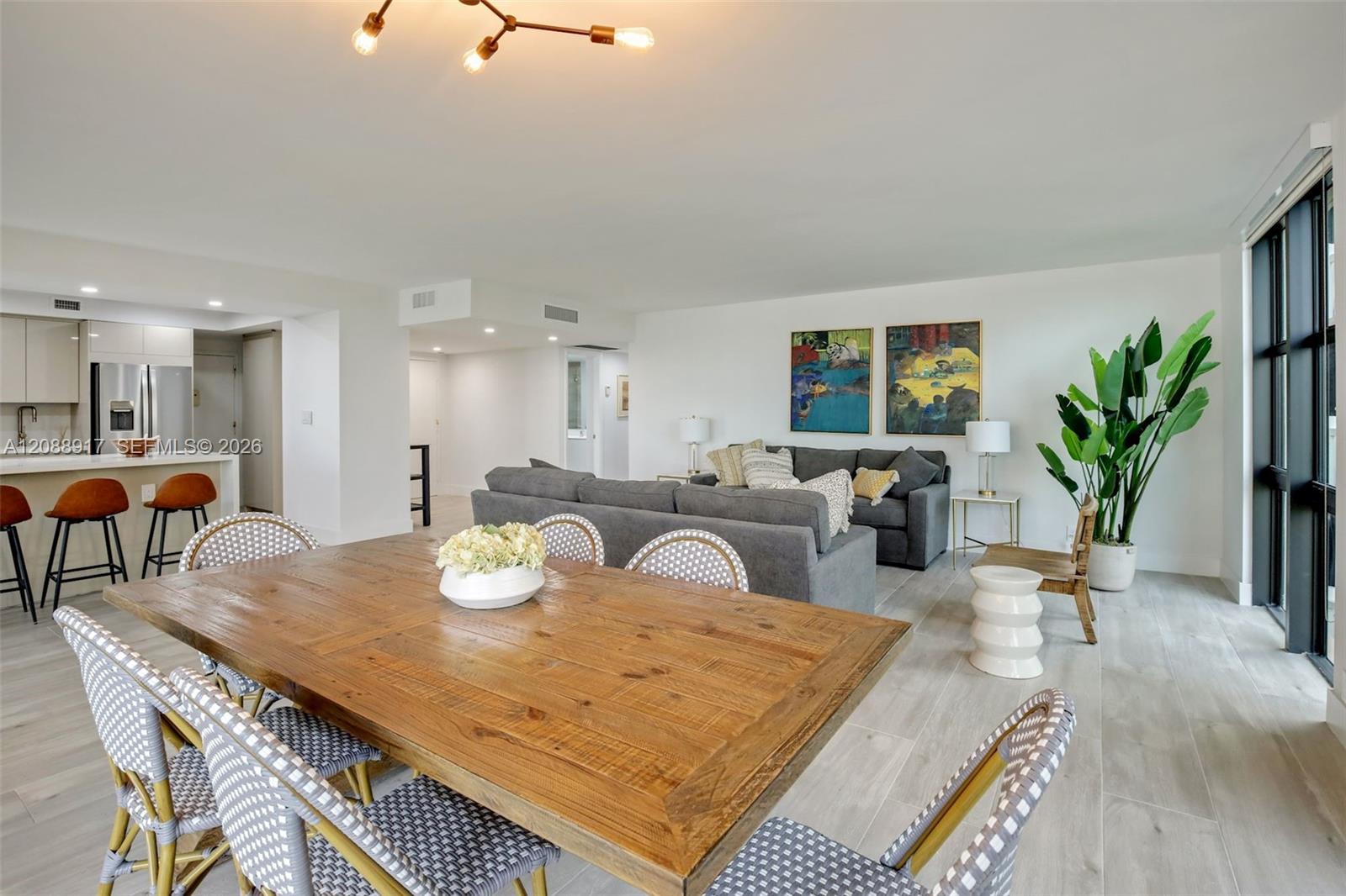Open-plan condo living and dining area with a large wood table and gray sectional.