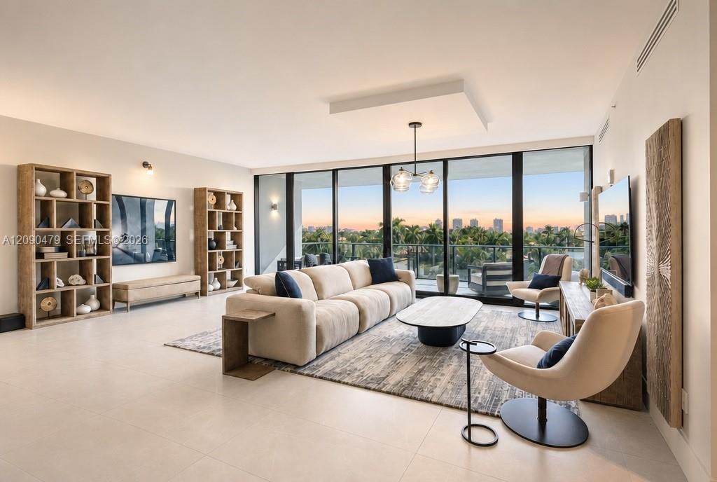 Living room with a cream sectional and floor-to-ceiling windows overlooking palms and a distant skyline.