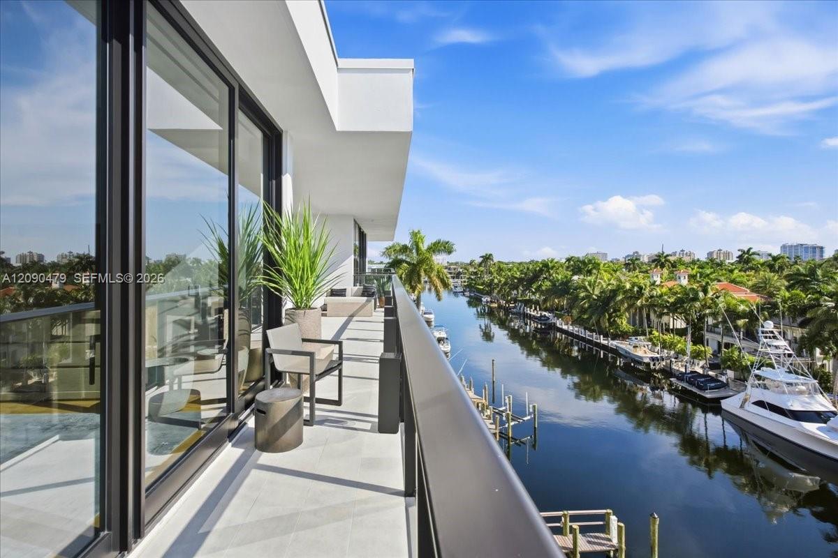 High-rise balcony overlooking a palm-lined canal with docked boats.