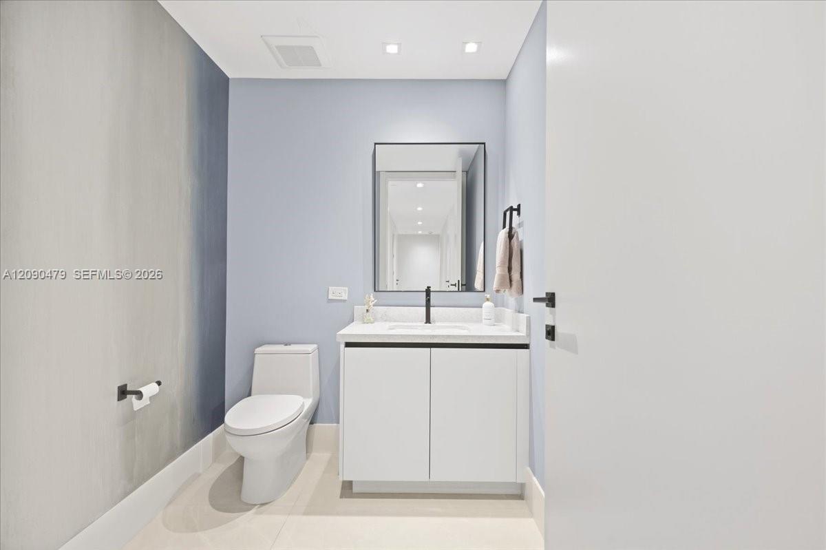 Bathroom with floating white vanity, black faucet, large mirror, and toilet.