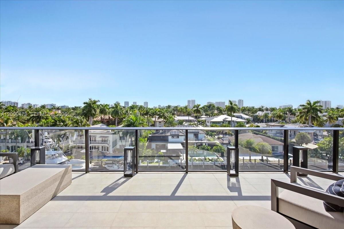 Penthouse balcony overlooking a canal, palm-lined homes, and the distant skyline.