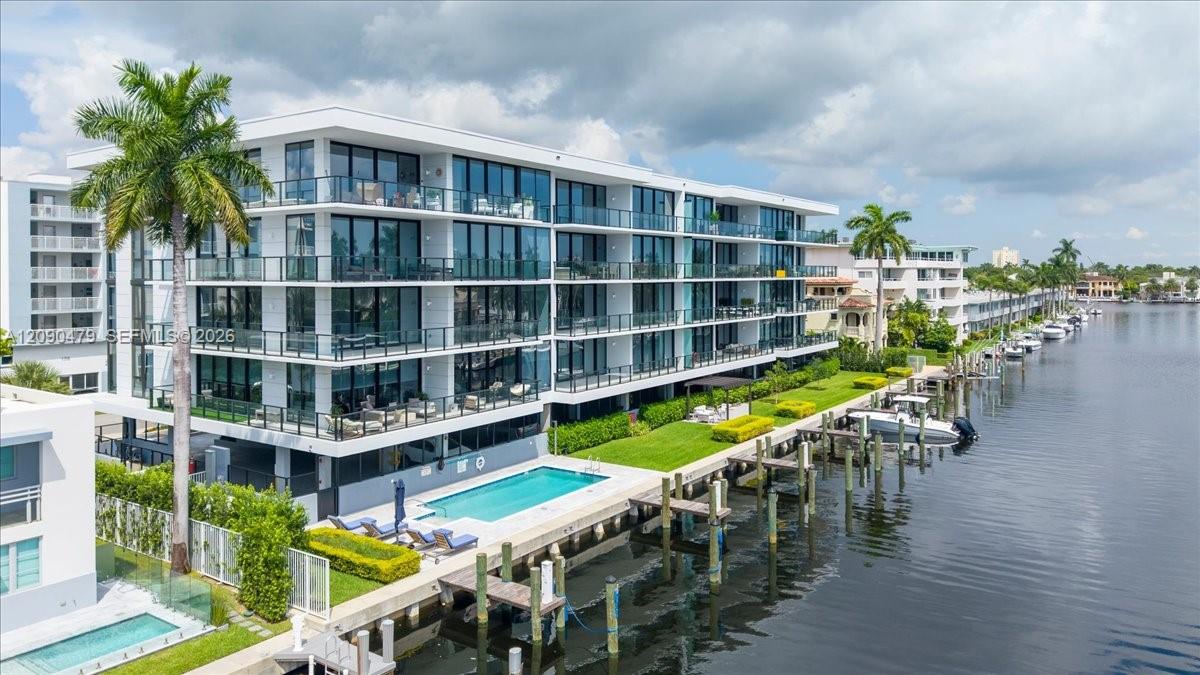 Modern waterfront condominium with glass balconies, a pool, and private docks along the canal.