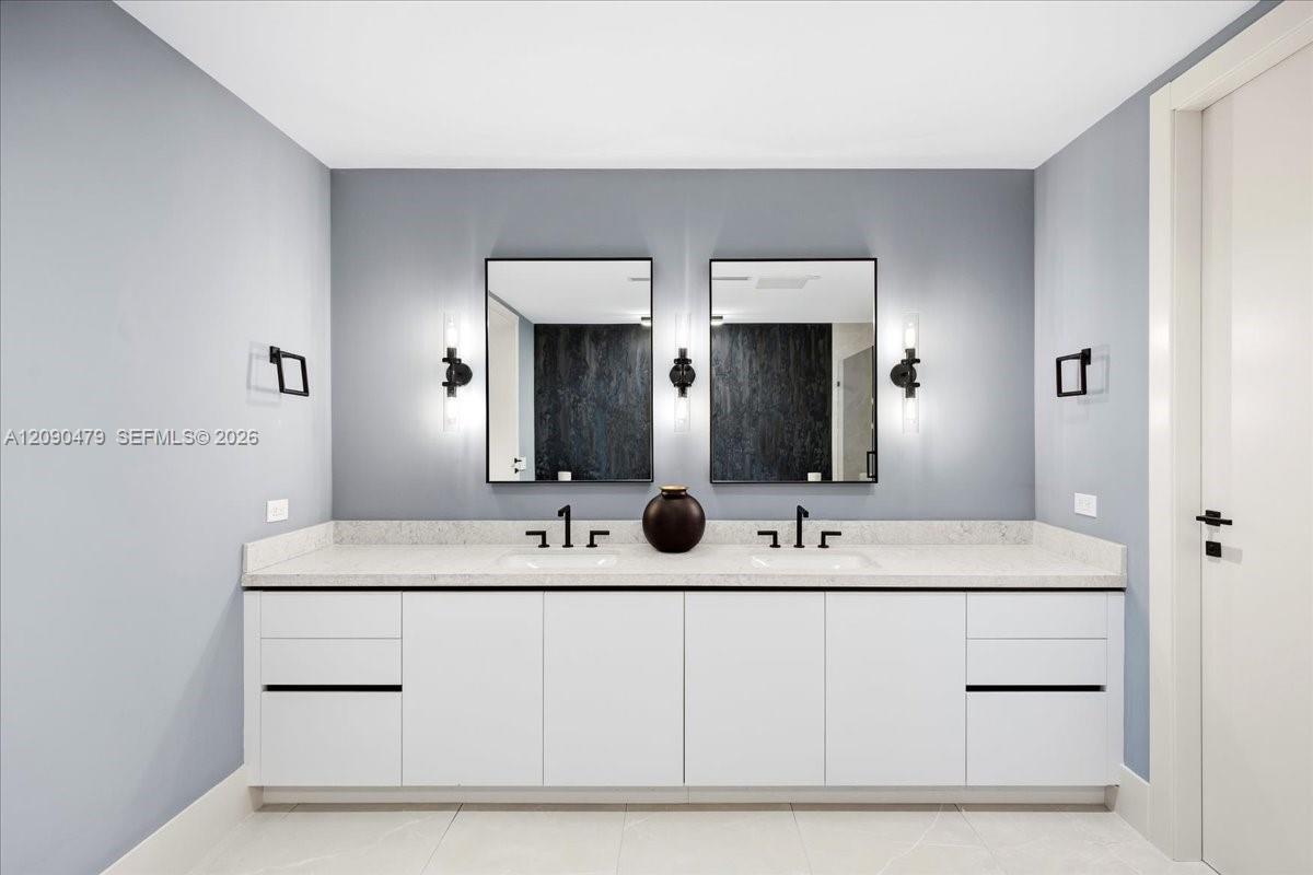 Bathroom with a white double vanity, pale stone counter, and two black-framed mirrors.