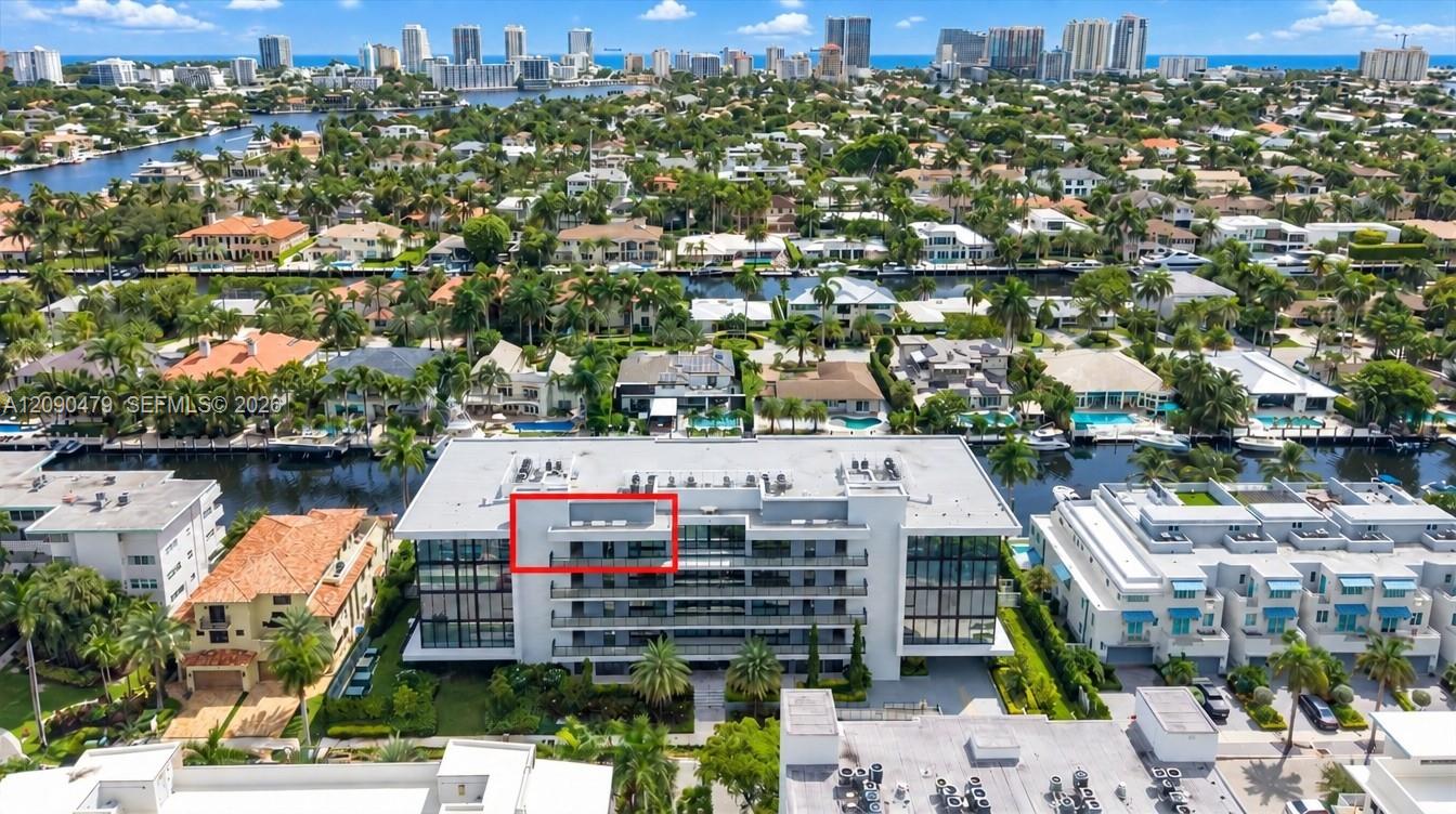 Aerial view of waterfront condominium, with the penthouse outlined in red and city skyline beyond.