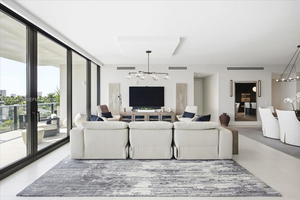 Living room with a white sectional sofa and floor-to-ceiling glass doors opening to a balcony.