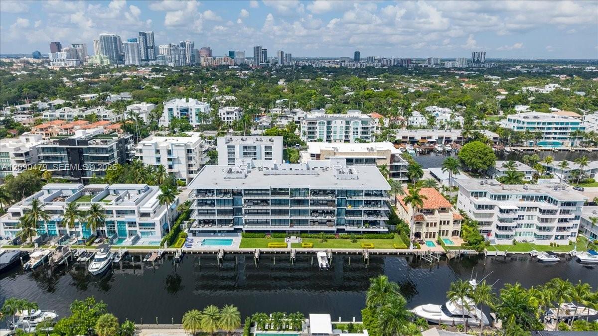 Waterfront condominium complex with a pool and docks beside a canal, with the Fort Lauderdale skyline in the distance.