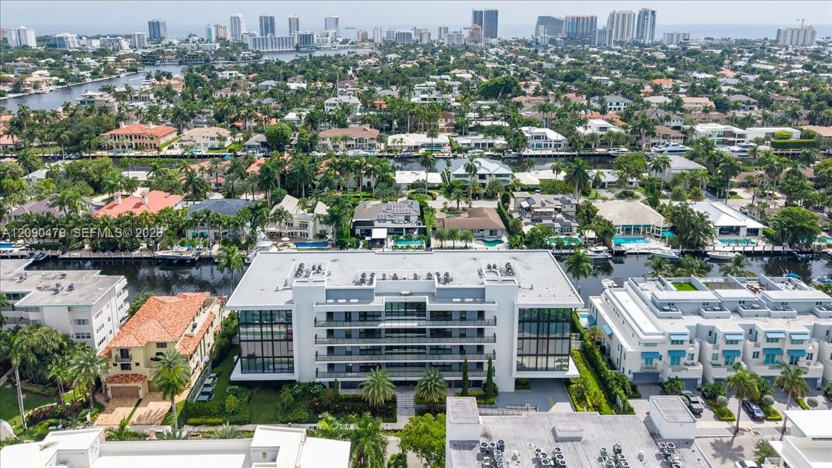 Aerial view of a canal-front condominium, with palm-lined homes and the Fort Lauderdale skyline beyond.