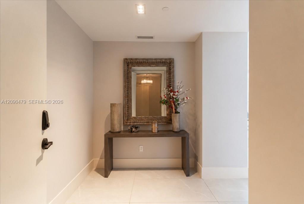 Condo entry foyer with a dark console table, ornate mirror, and flower arrangement.