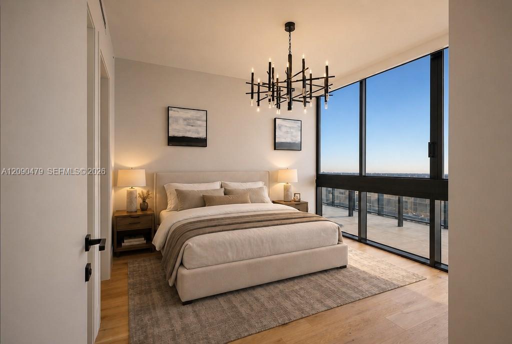 Contemporary bedroom with a king-size bed, geometric chandelier, and floor-to-ceiling windows overlooking a balcony.