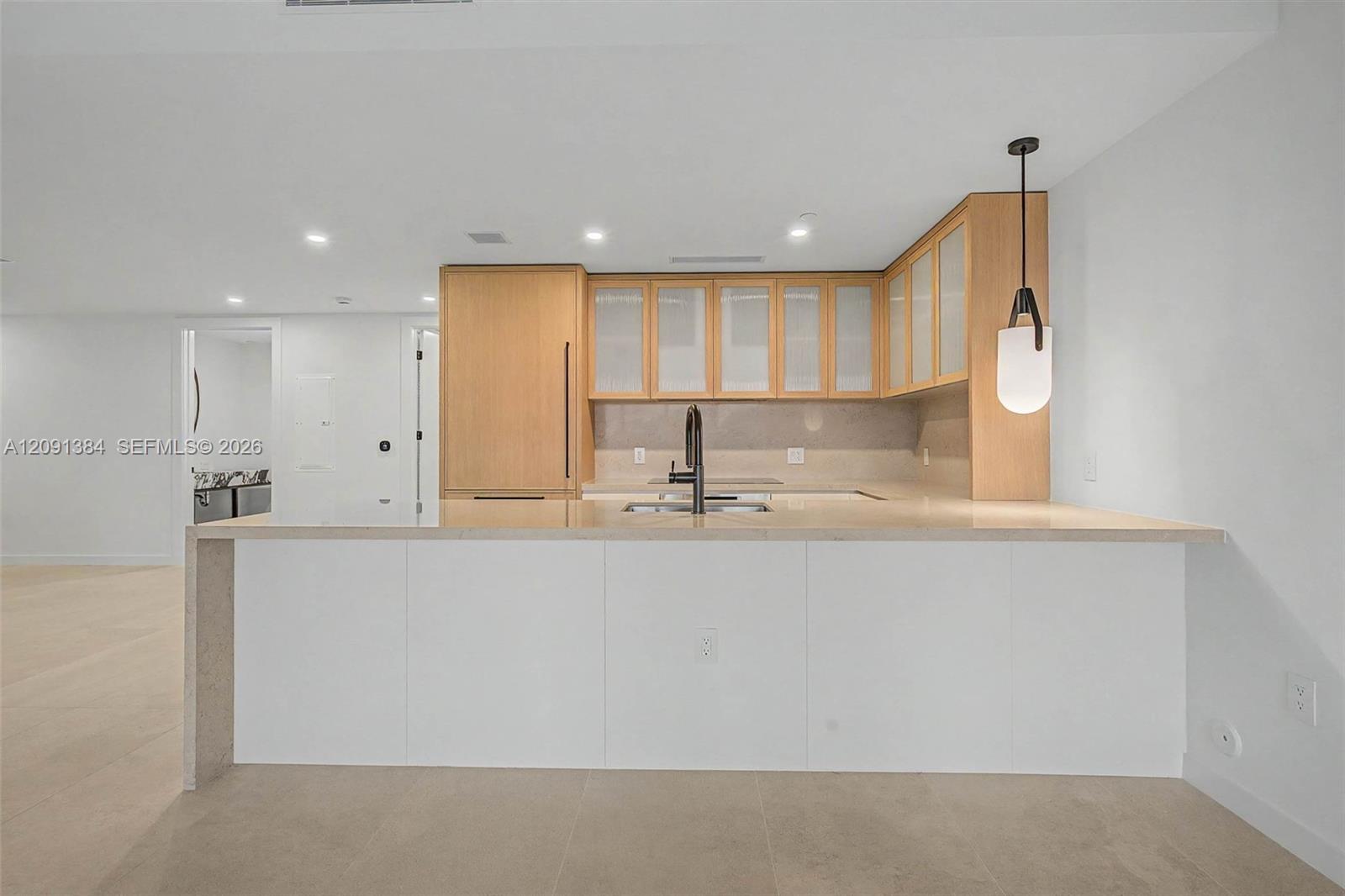 Modern kitchen with pale wood cabinets, frosted-glass doors, and a large white island.