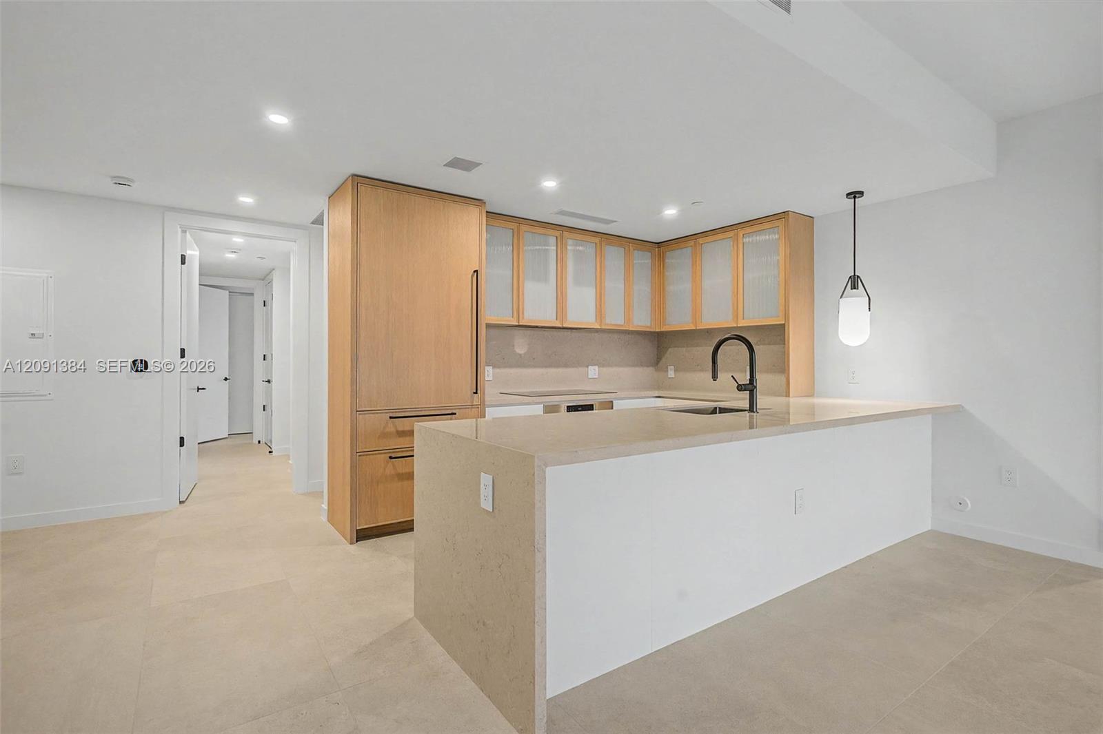 Modern kitchen with light wood cabinets, frosted-glass doors, and a large waterfall island.