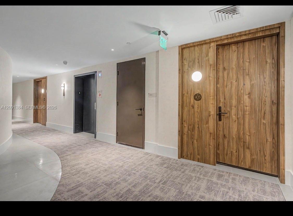 Condominium hallway with wood-paneled doors, including unit 405, and a carpeted floor.