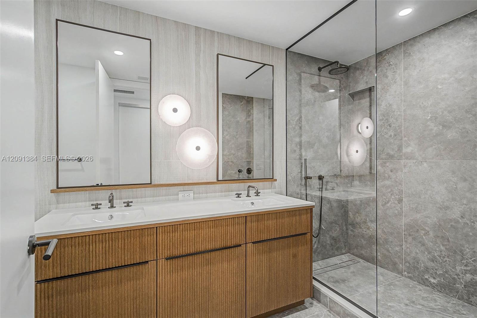 Modern bathroom with a double-sink wood vanity and a glass-enclosed gray-tile shower.