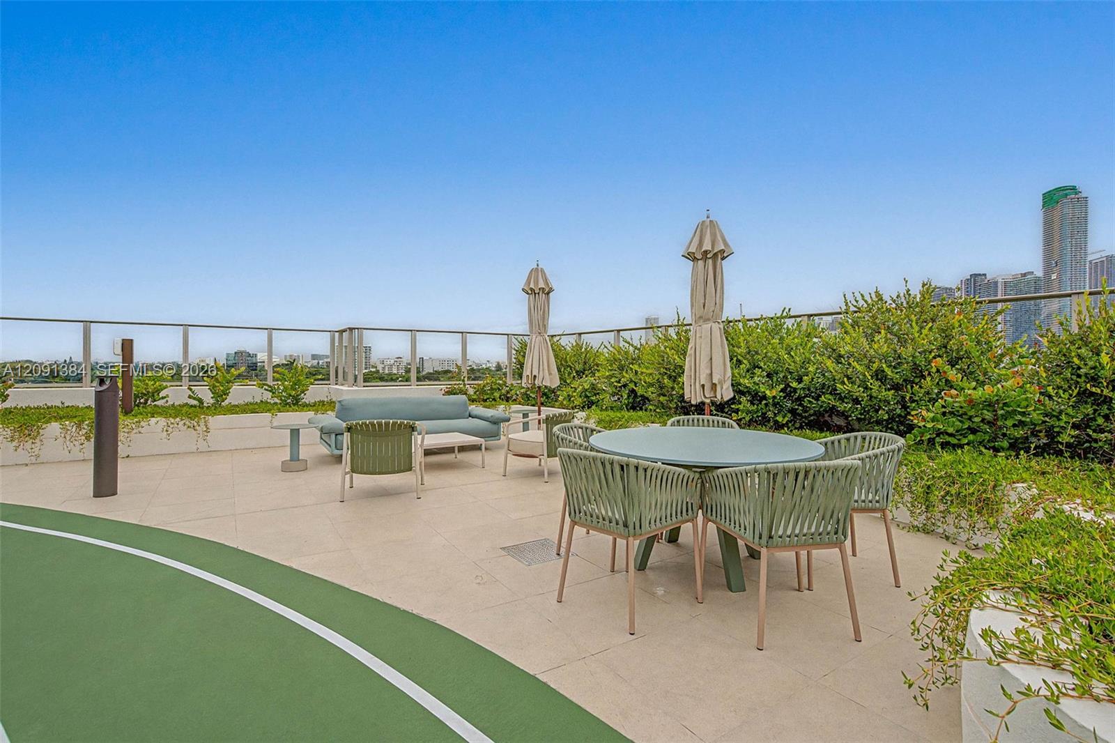 Rooftop terrace with outdoor dining, lounge seating, hedges, and Miami skyline views.
