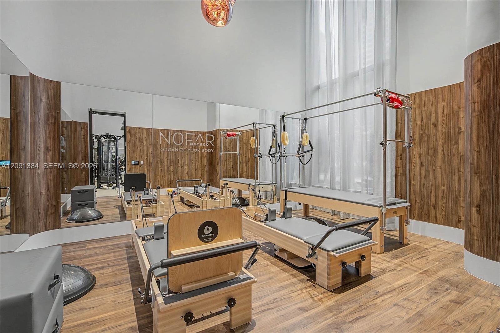 Fitness studio with wooden Pilates reformers, mirrored wall, and NOFAR Method lettering.