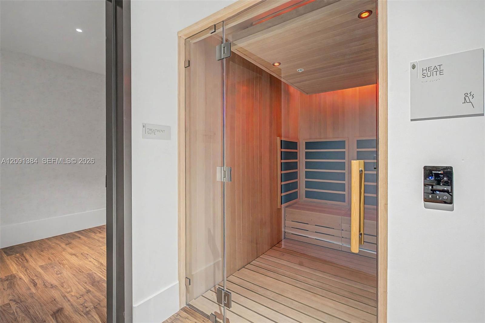 Cedar sauna with glass door, built-in benches, and a wall-mounted control panel.
