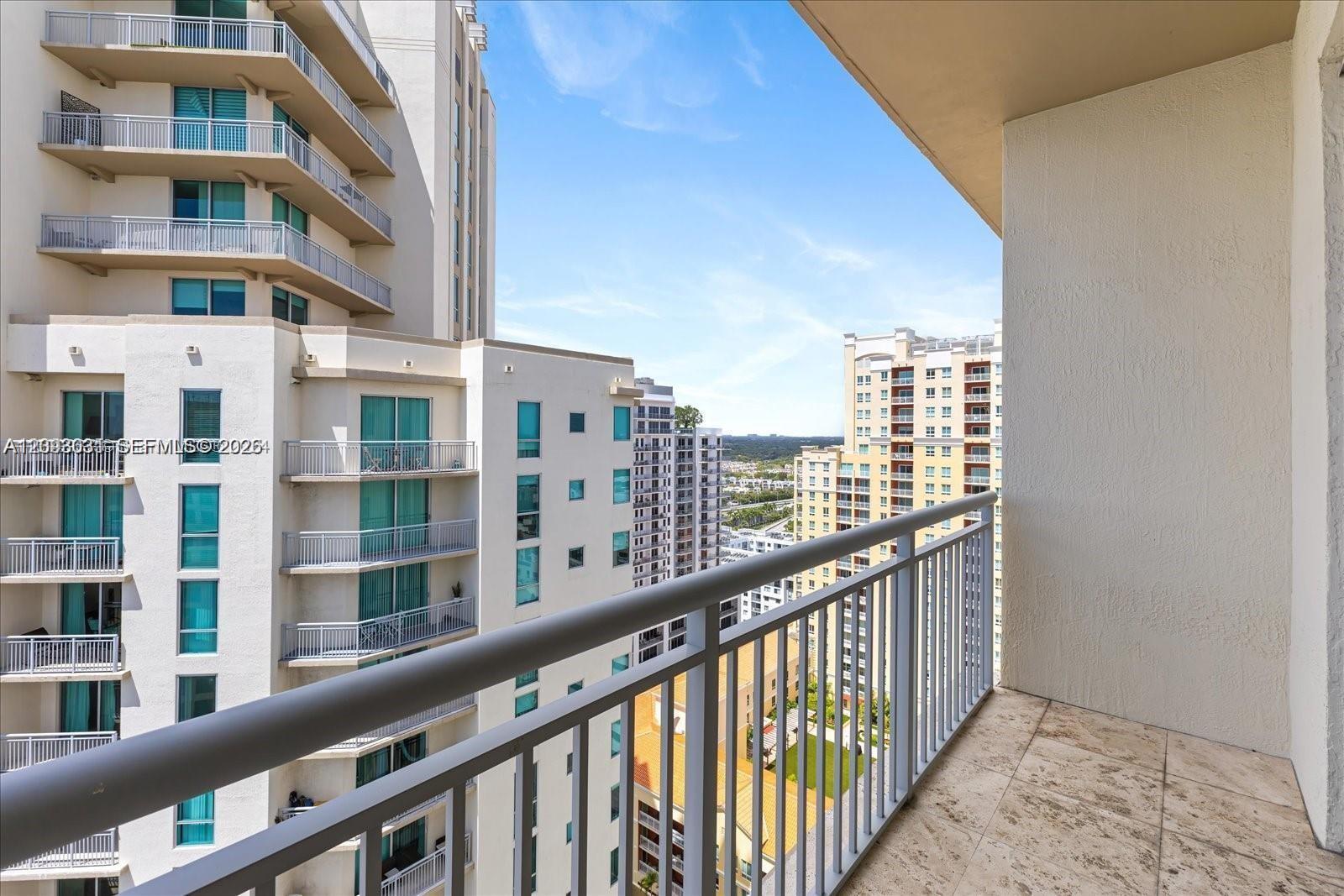 High-rise condo balcony overlooking neighboring apartment buildings and the distant city.