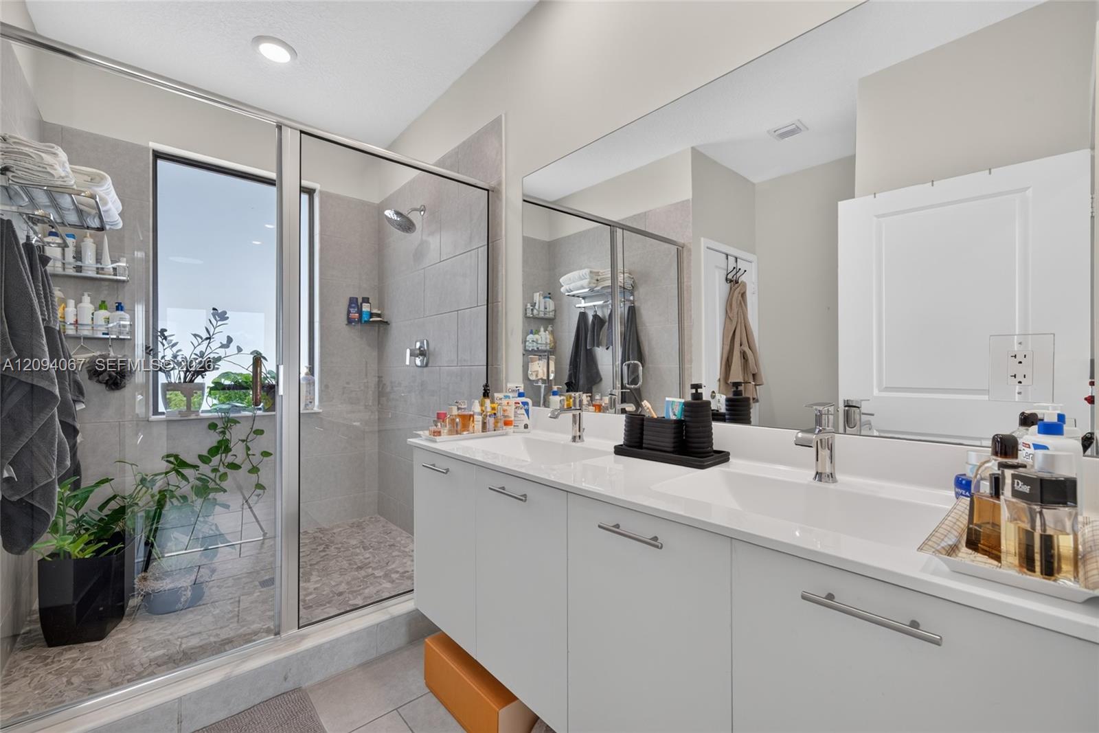 Modern bathroom with a glass walk-in shower and long white double-sink vanity.