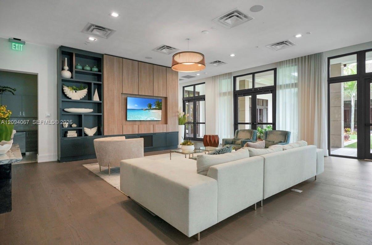 Contemporary living room with a white sectional sofa, built-in shelving, and tall windows.
