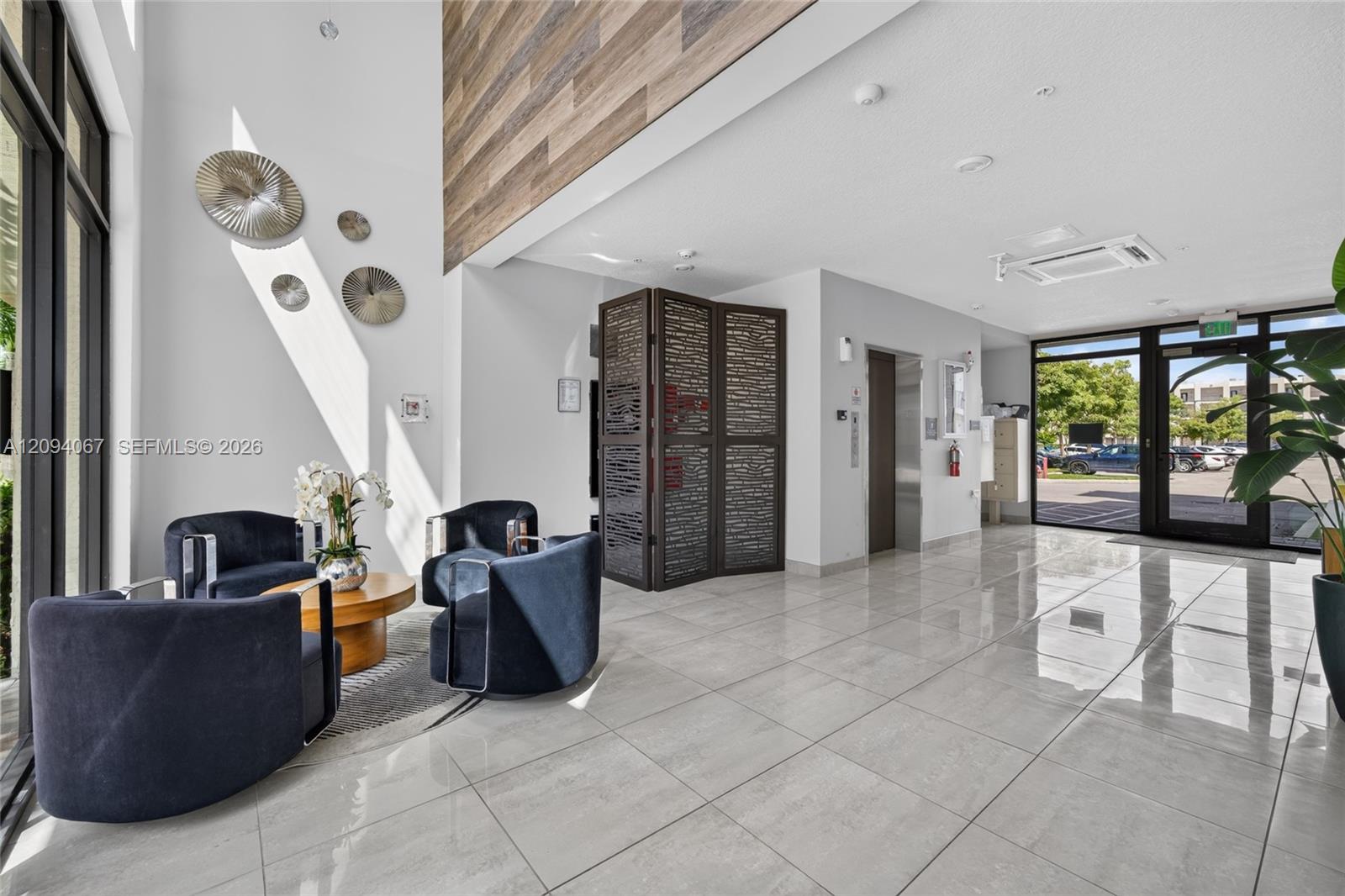 Building lobby with navy lounge chairs, glossy tile floors, and glass entrance doors.