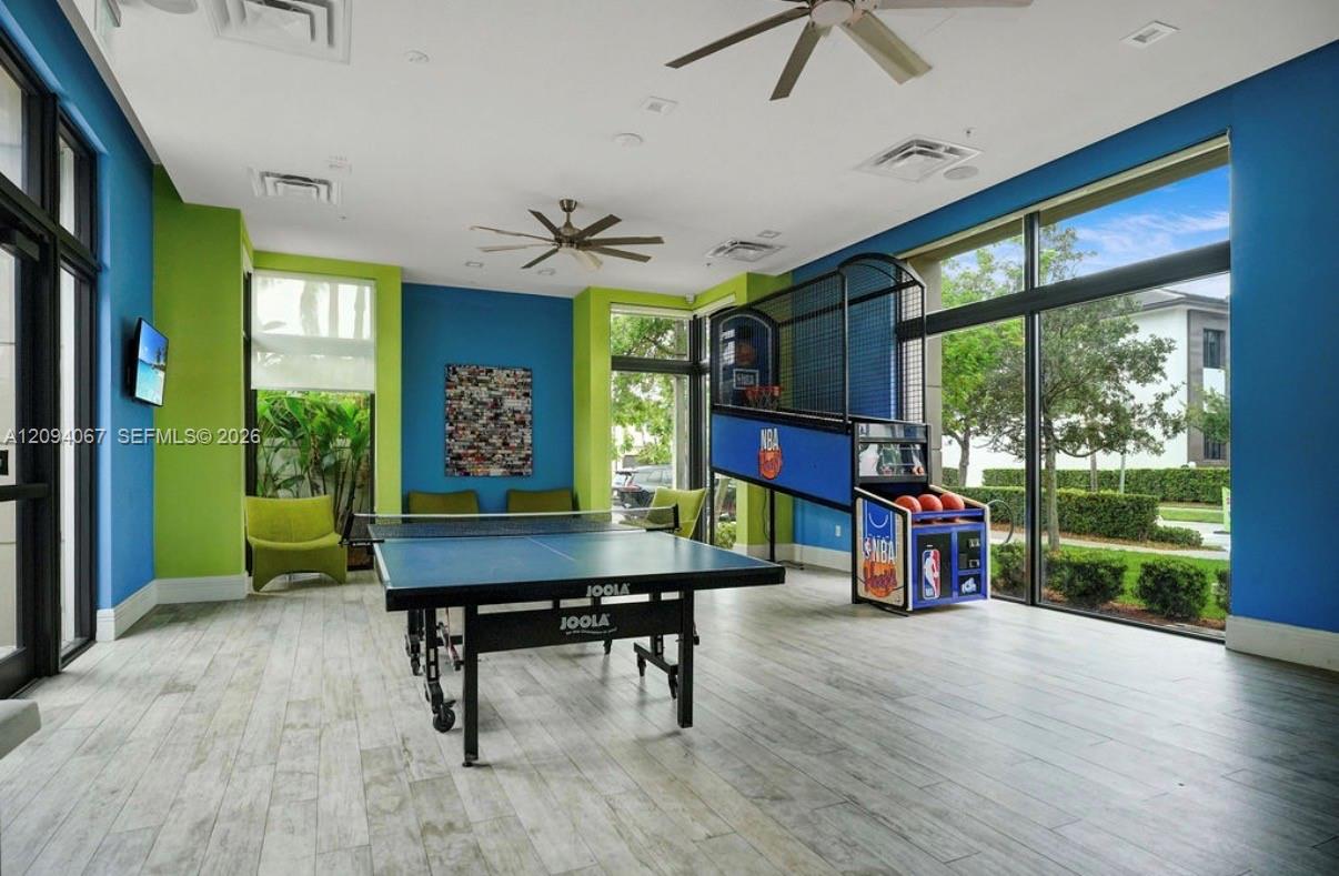 Recreation room with a table-tennis table, NBA basketball arcade game, and large windows.