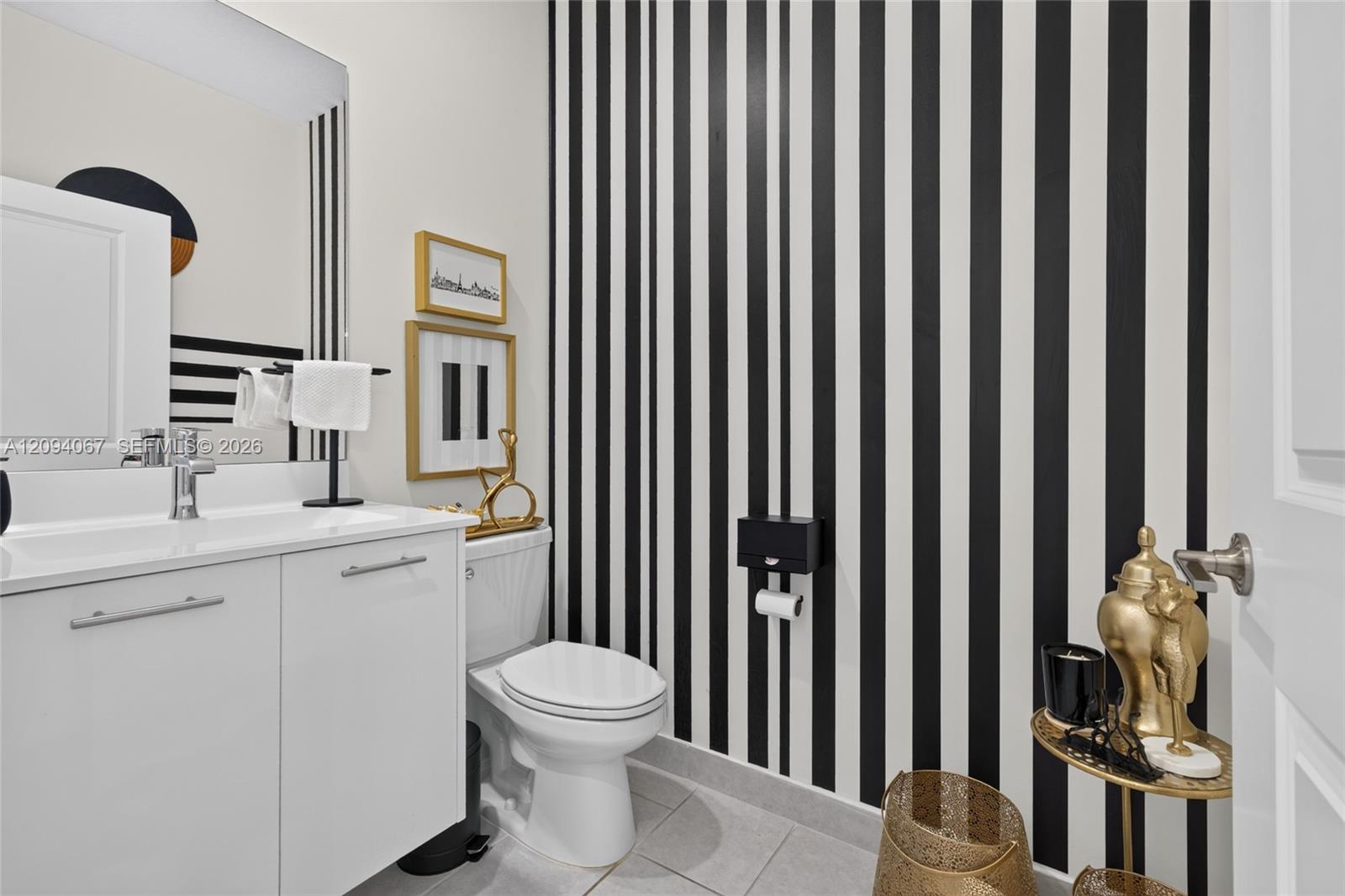 Bathroom with a white vanity, toilet, and bold black-and-white striped wall.