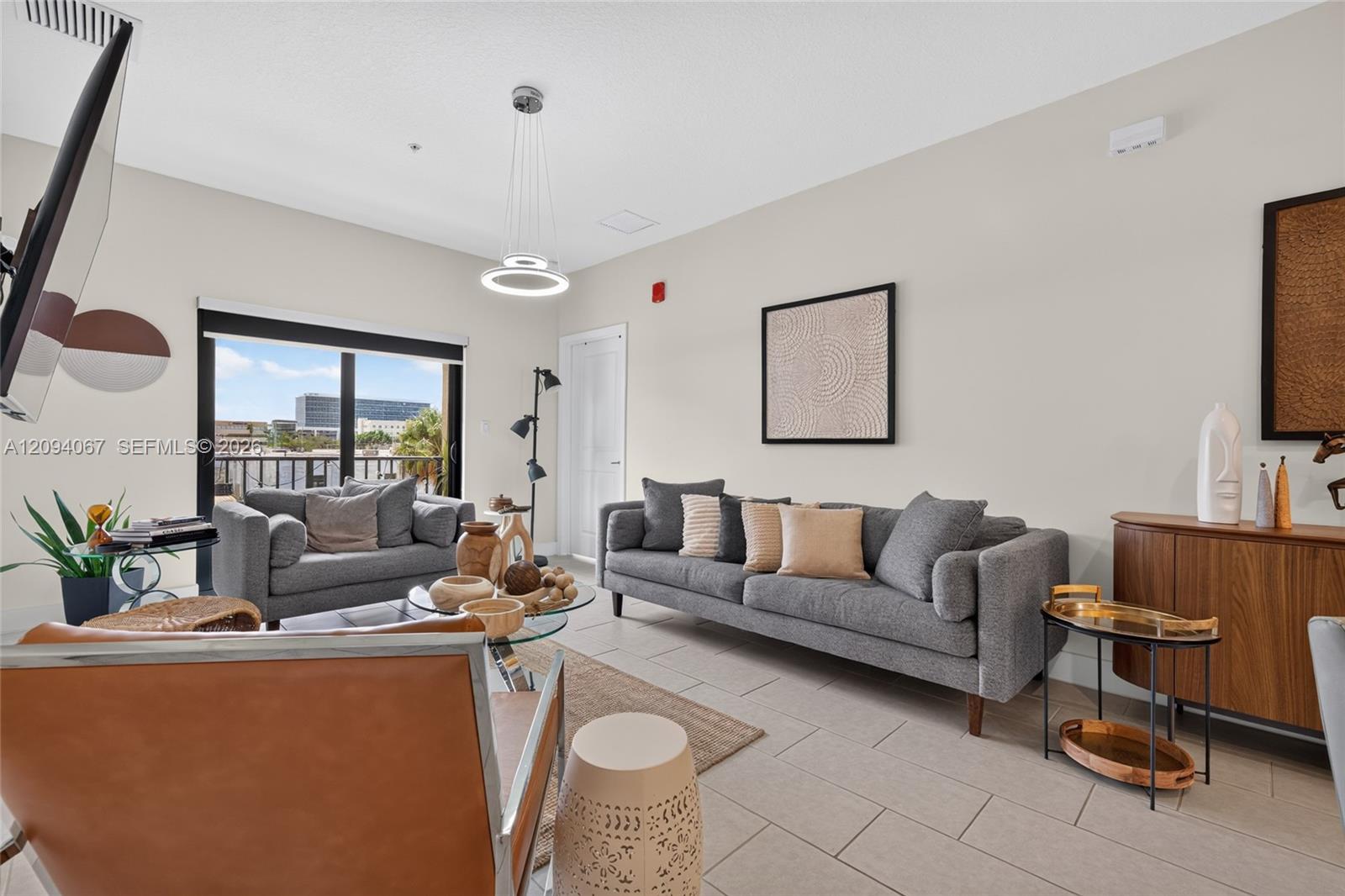 Living room with gray sofas and a balcony view through sliding glass doors.
