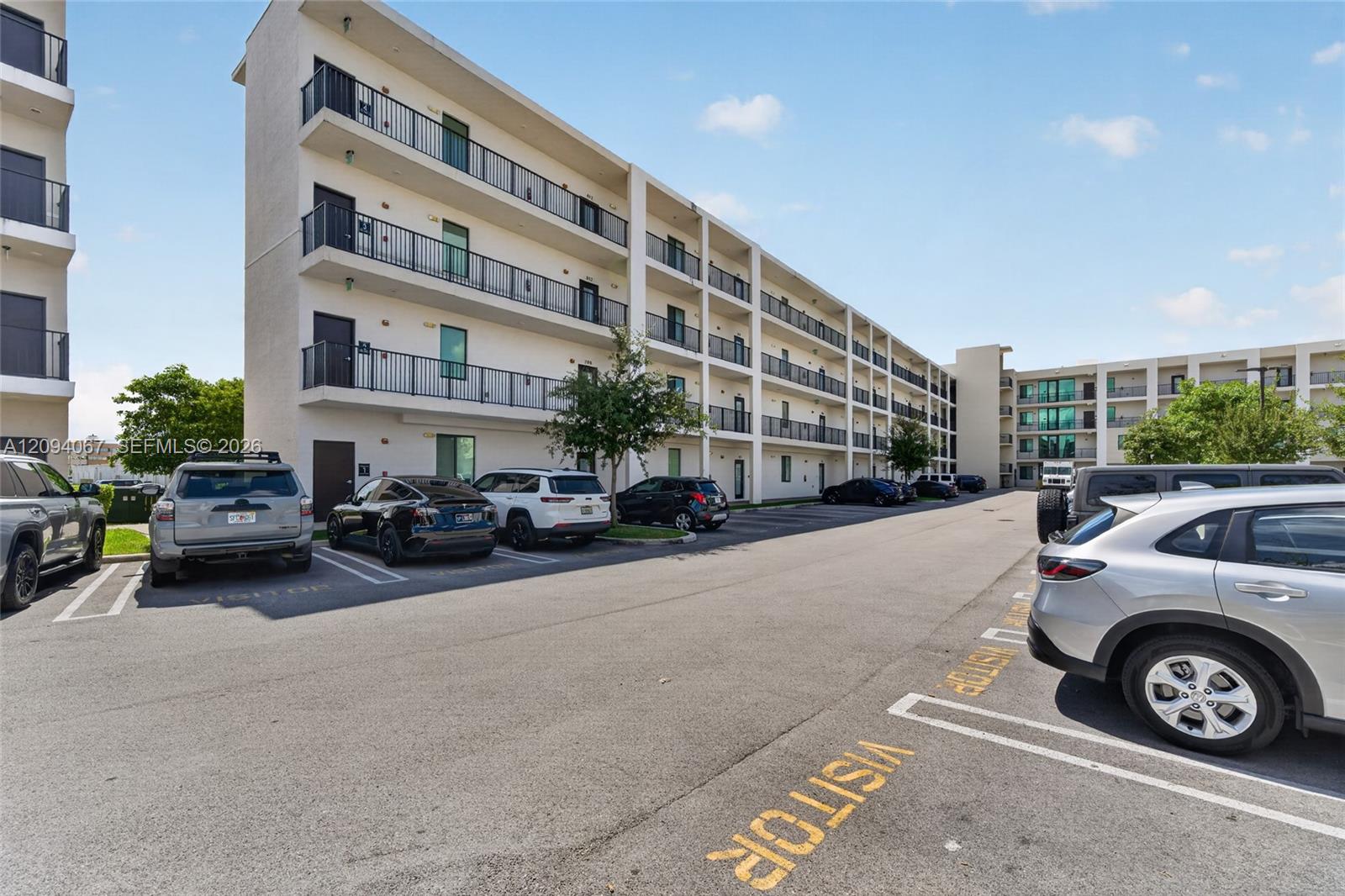 Apartment building with long balconies beside a parking lot with reserved spaces.