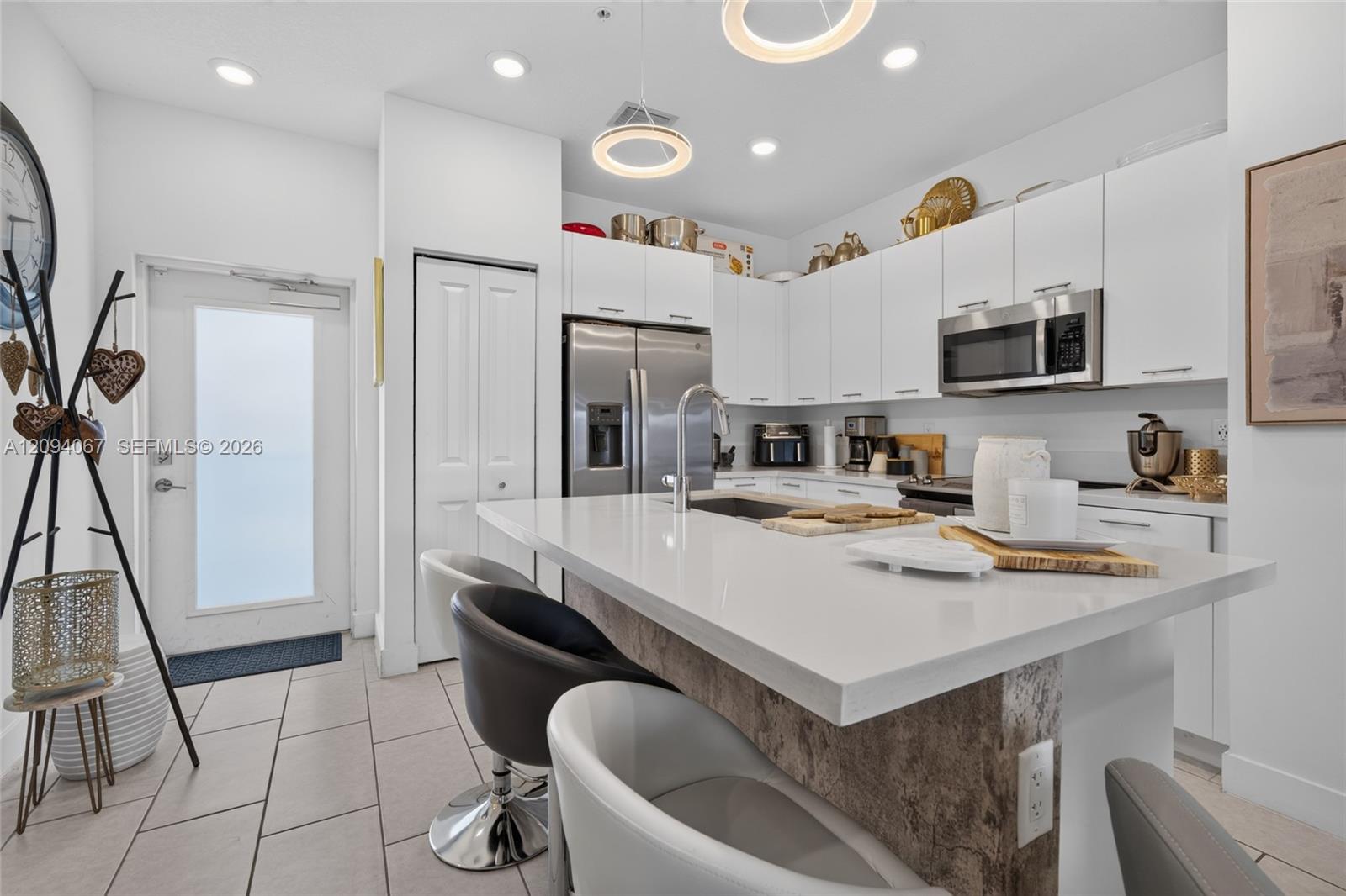 Modern kitchen with white cabinets, stainless appliances, and a large island with bar seating.