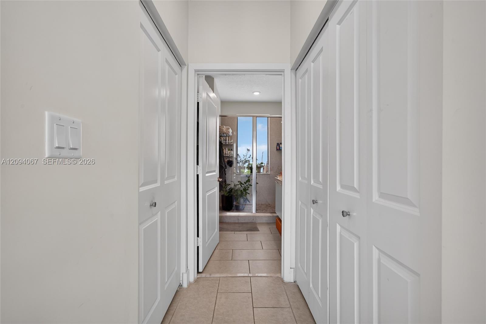 Tiled hallway with white paneled doors leading to a glass-enclosed shower.