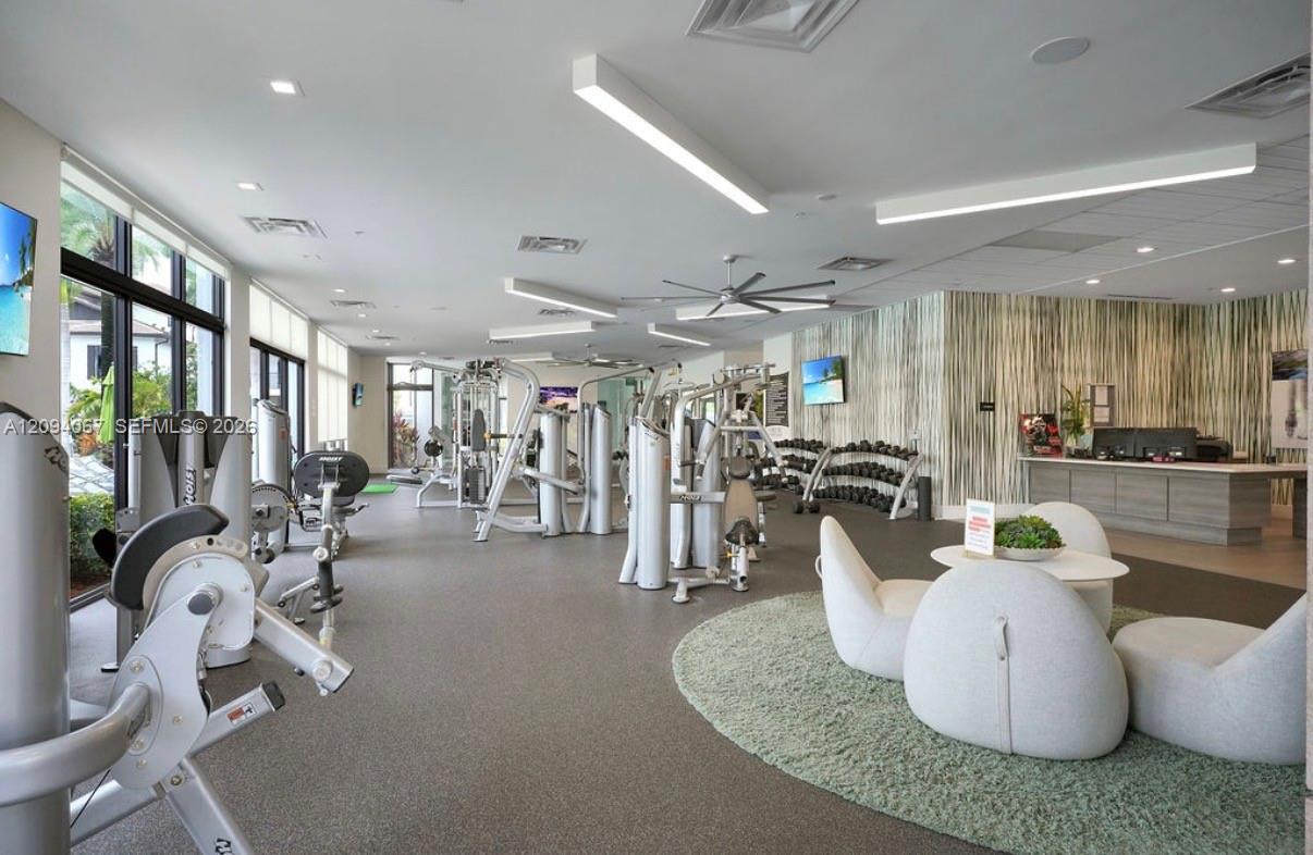 Fitness center with weight machines, dumbbells, large windows, and a lounge seating area.