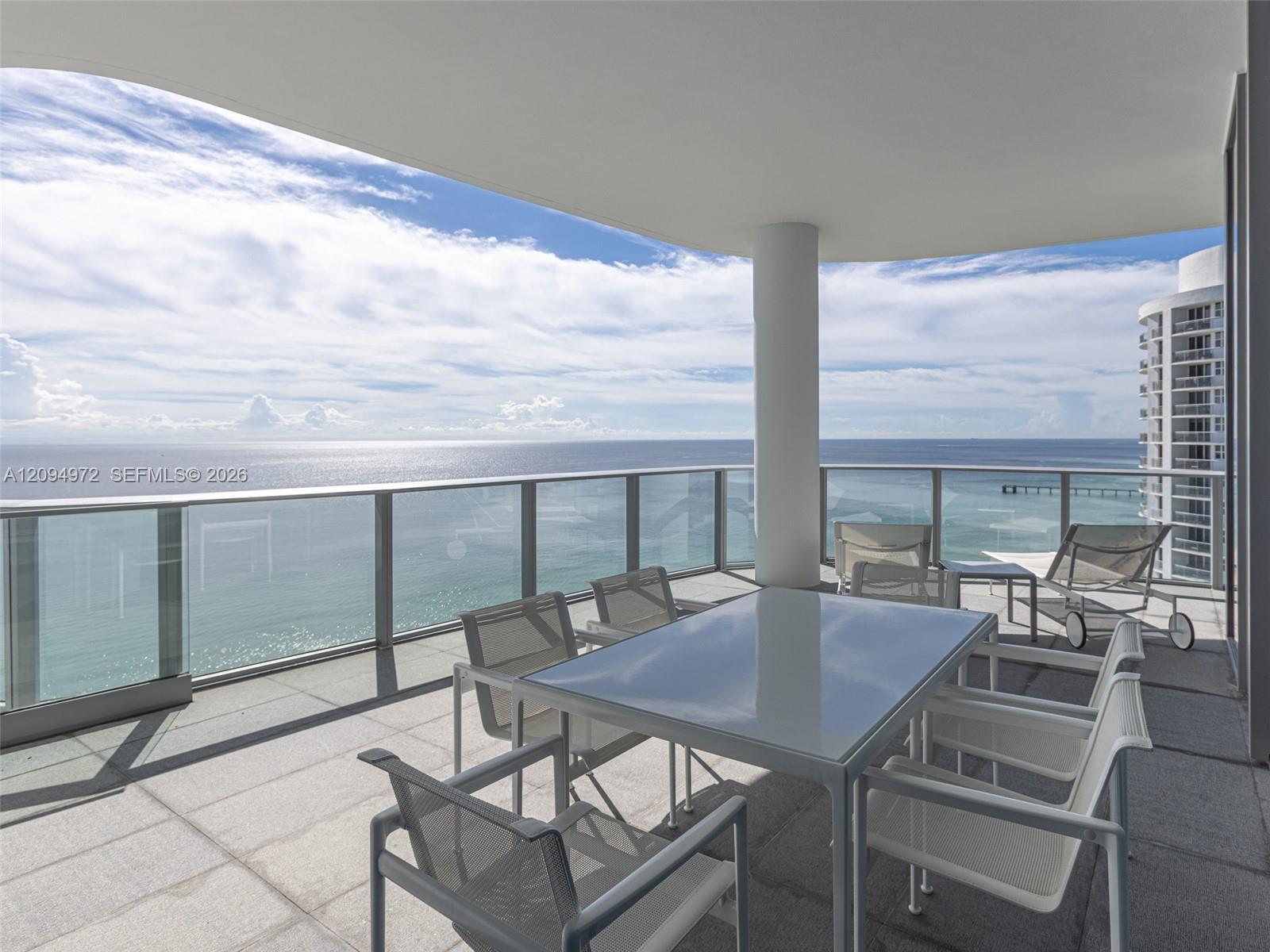Oceanfront balcony with outdoor dining furniture and a wide ocean view.