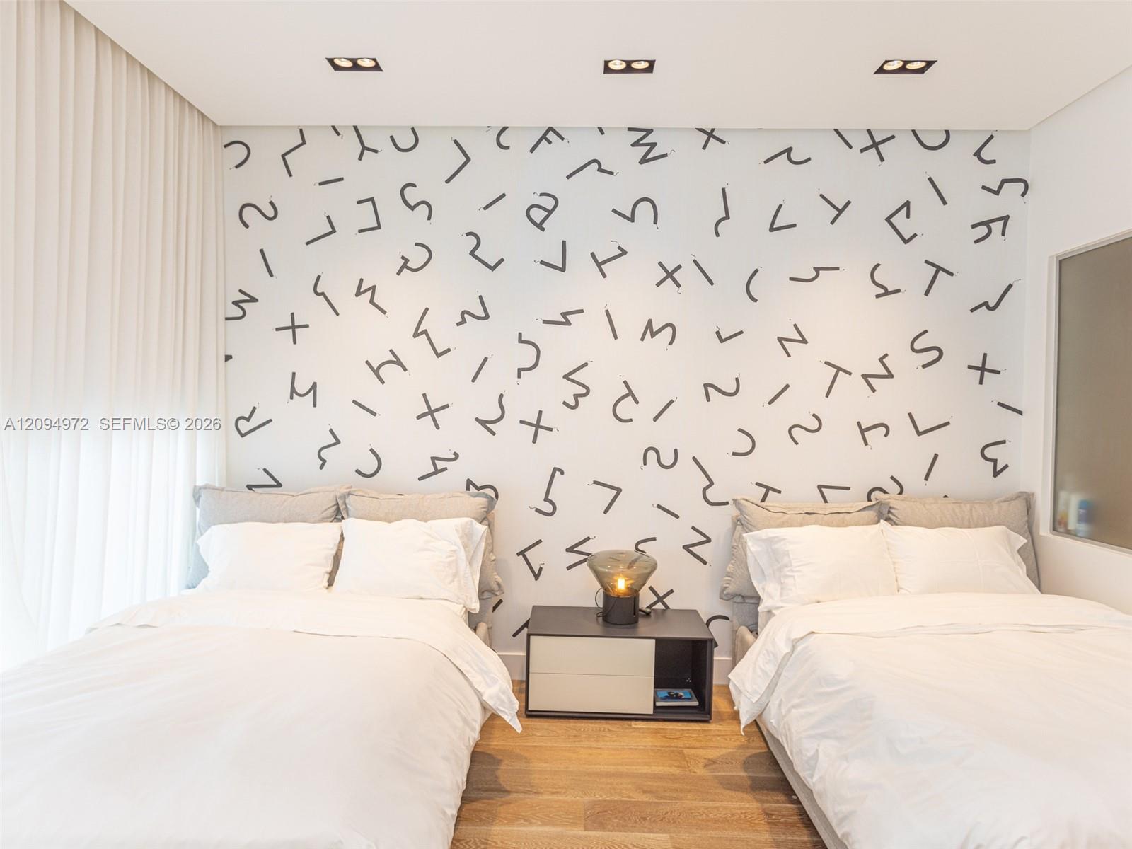 Bedroom with two white beds, a shared nightstand, and a bold black-and-white patterned wall.